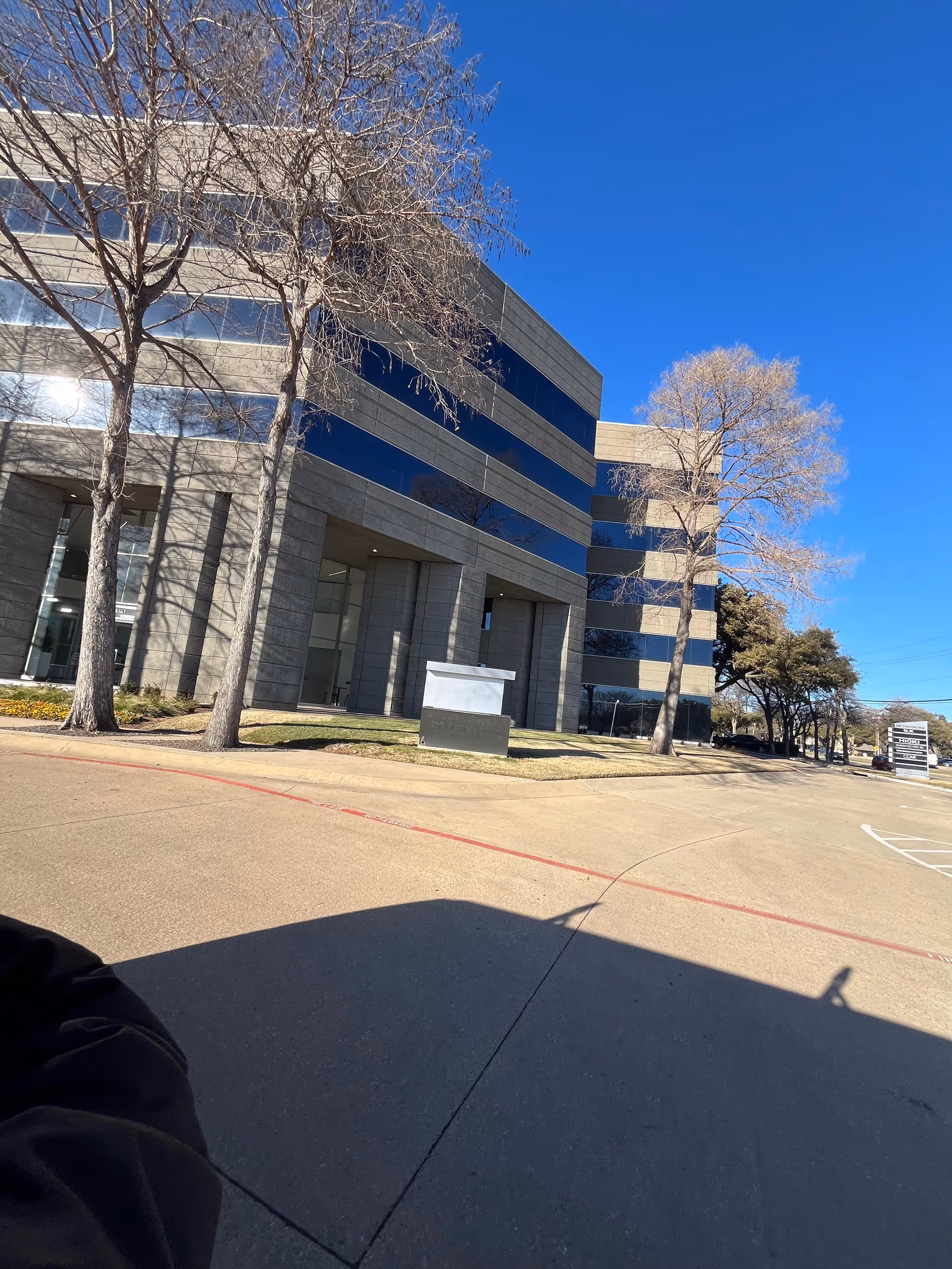 CareGivers To Go facility exterior: modern building, leafless trees, blue sky.
