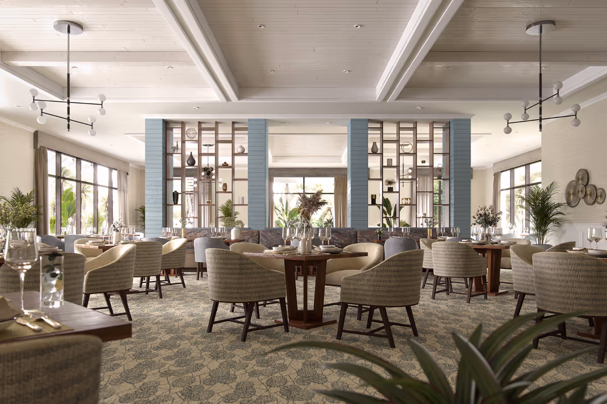 A bright, upscale dining room with multiple round tables, cushioned chairs, decorative shelving dividers, and large windows letting in natural light.