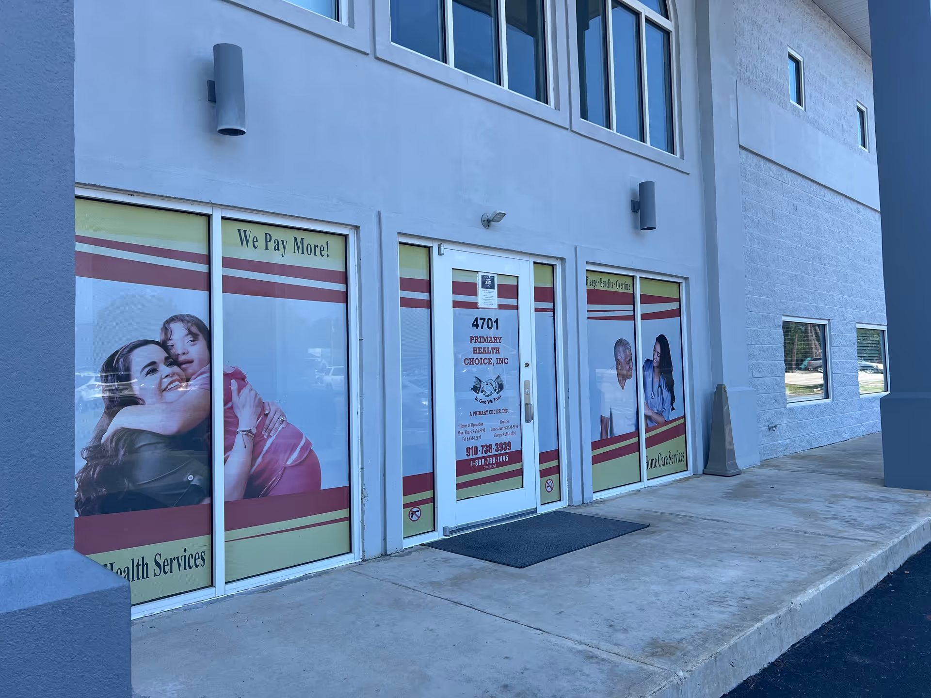 Front of a light blue building with glass doors and promotional posters for Primary Health Choice.