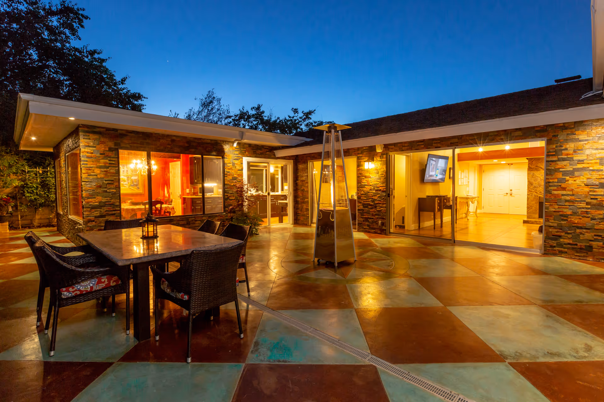 Outdoor courtyard at Casa Del Sol with colorful tiled patio, table, chairs, and warm building lighting.