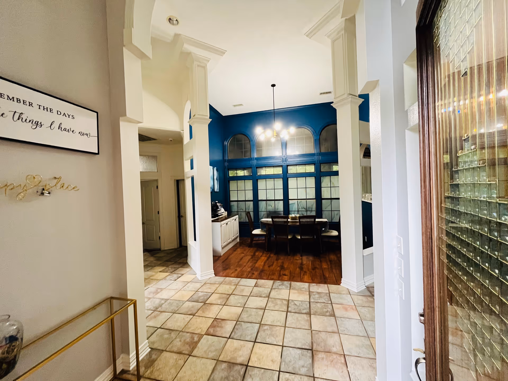 Interior dining area with blue wall, arched windows, and a wooden table.