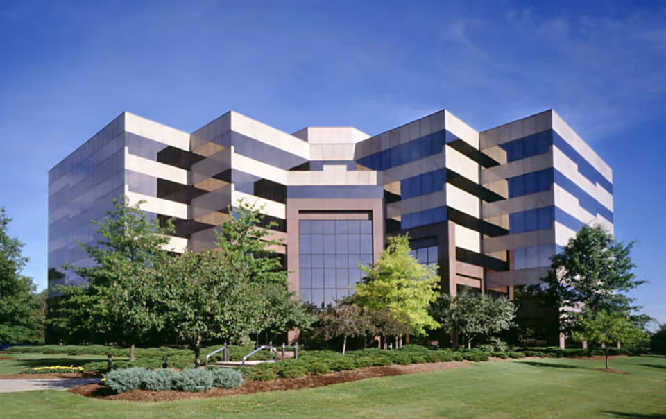 A modern, angular building with a glass entry and manicured surrounding lawn.