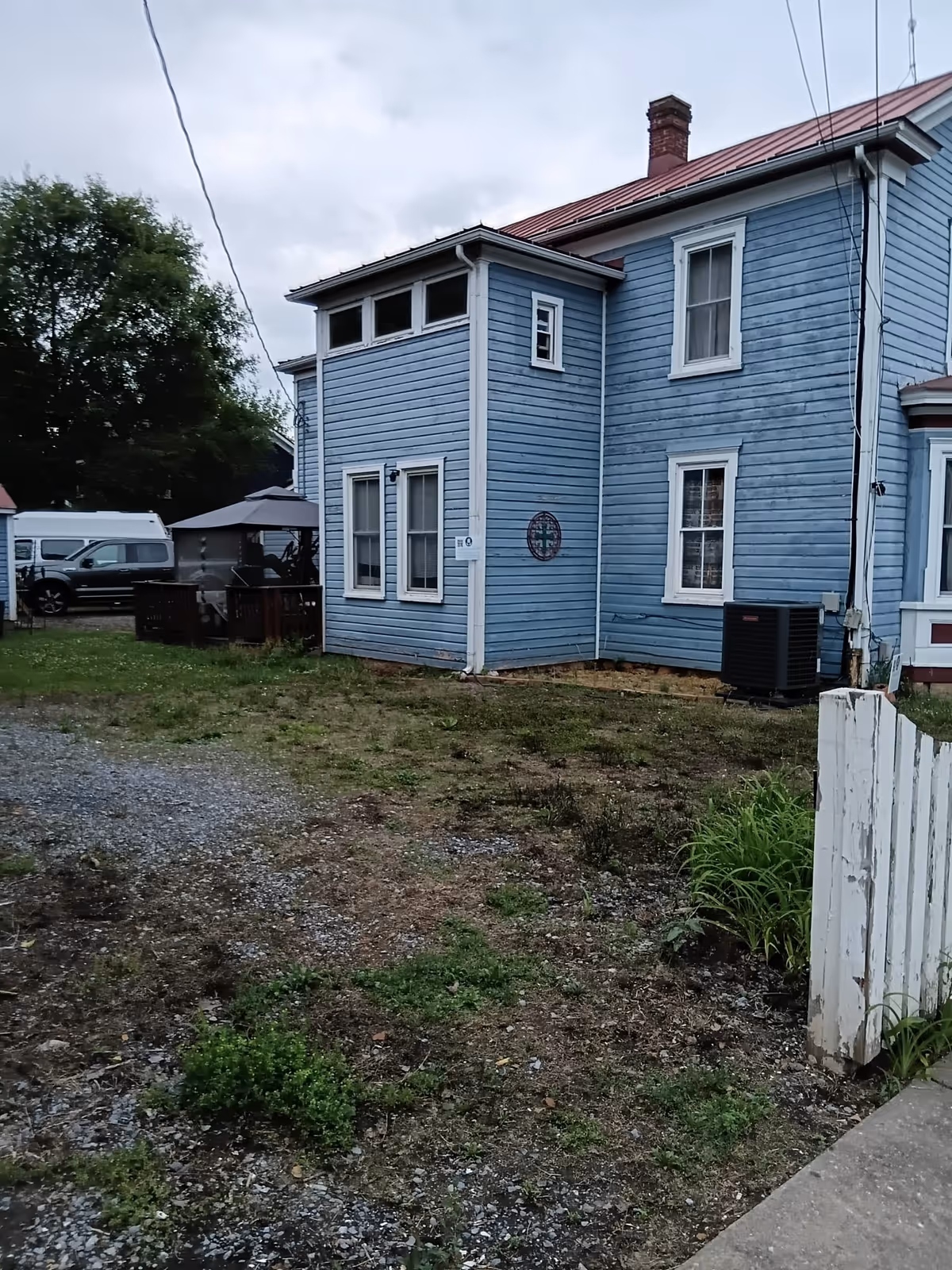Blue two-story wooden building with white trim and surrounding yard.