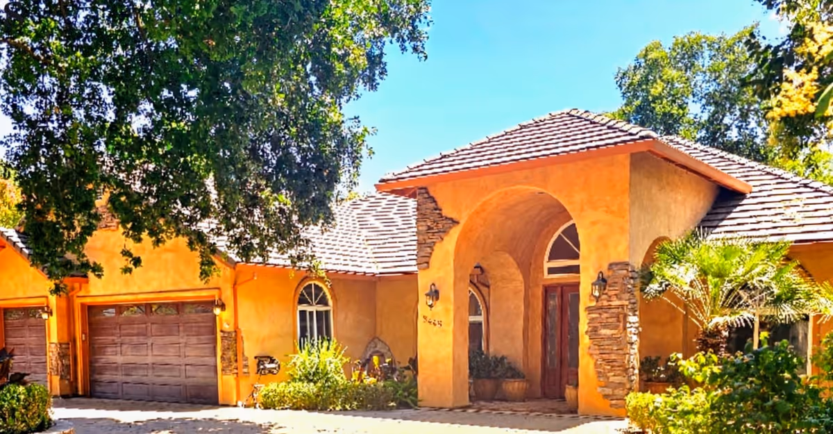 Orange stucco senior living facility with arched entry and stone accents.