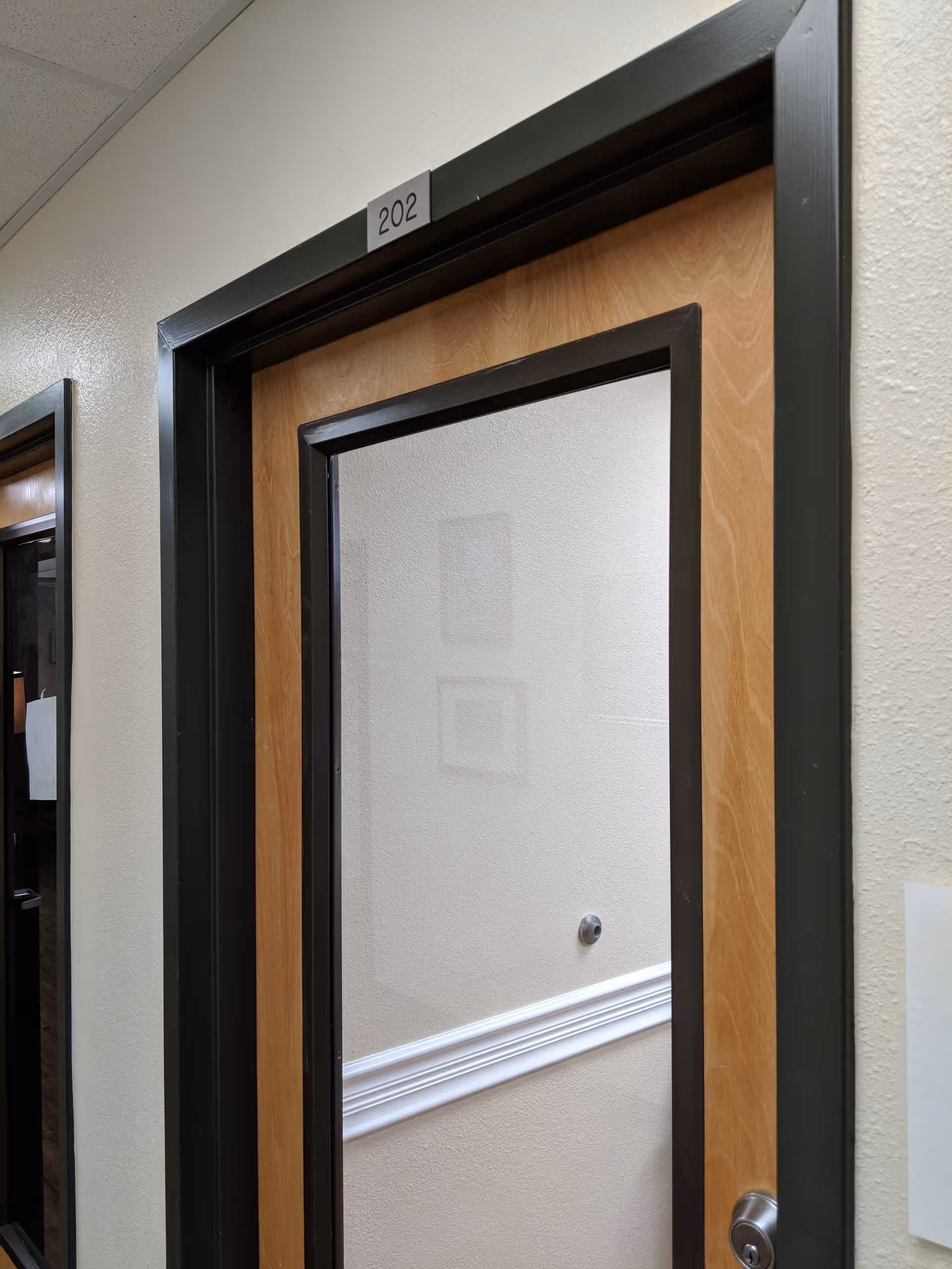 Interior hallway with a wooden door labeled 202 and beige walls