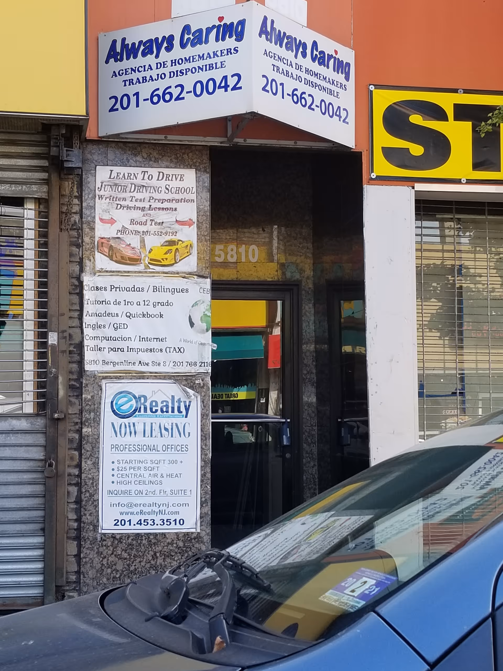Storefront with Always Caring signs and adjacent business ads, a parked car in front.