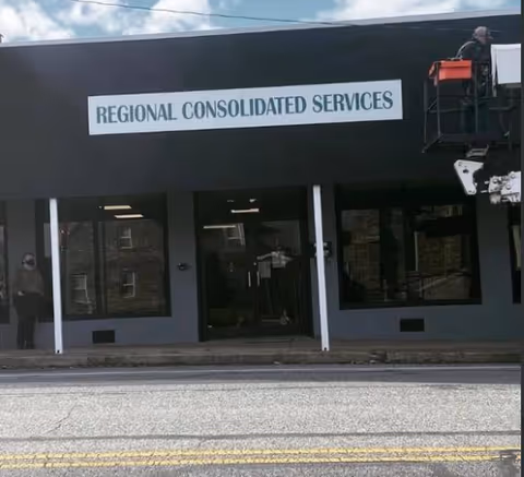 Exterior view of a building with a Regional Consolidated Services sign above storefront windows.