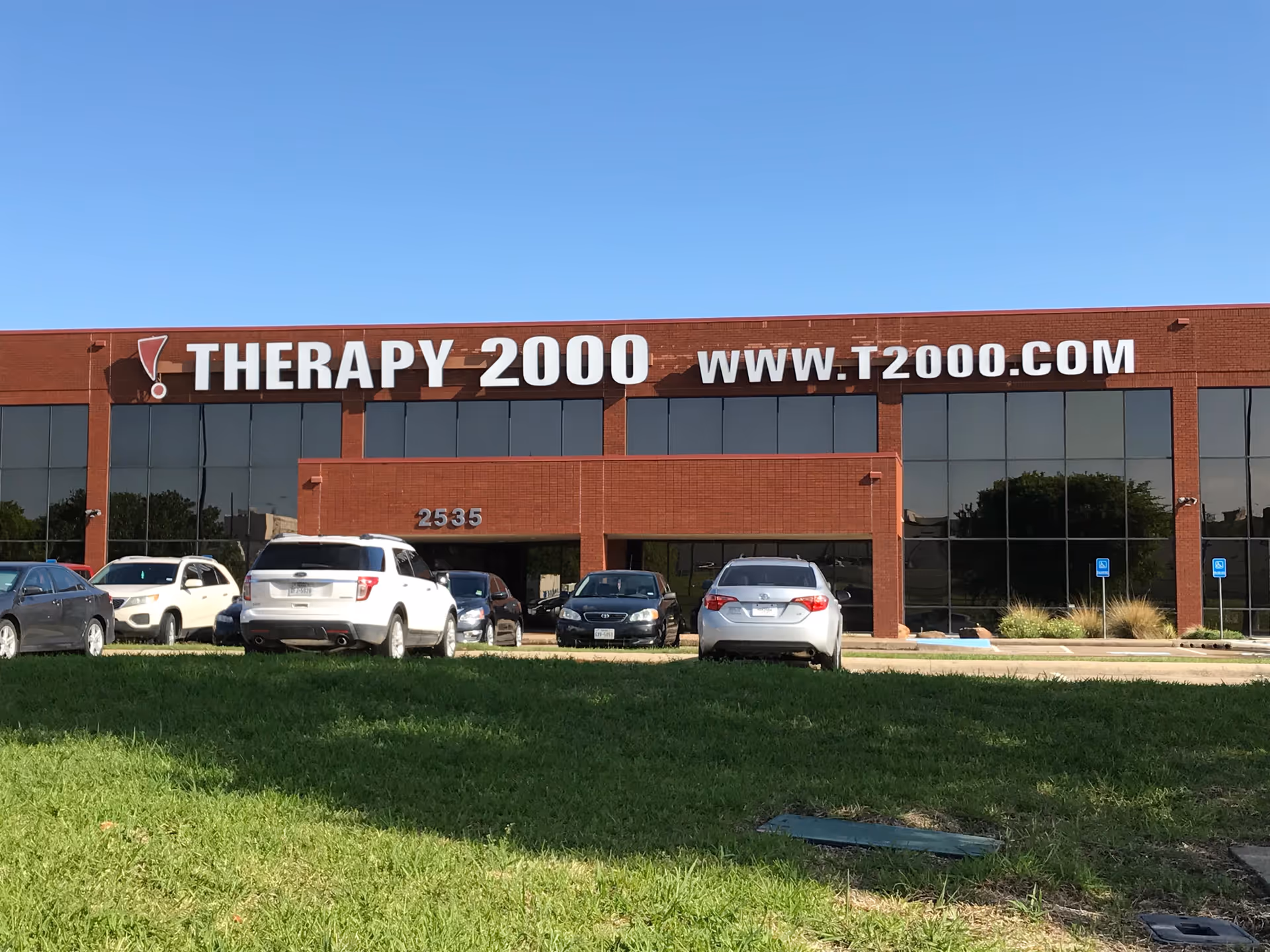 Brick therapy center with large glass windows and parked cars outside.