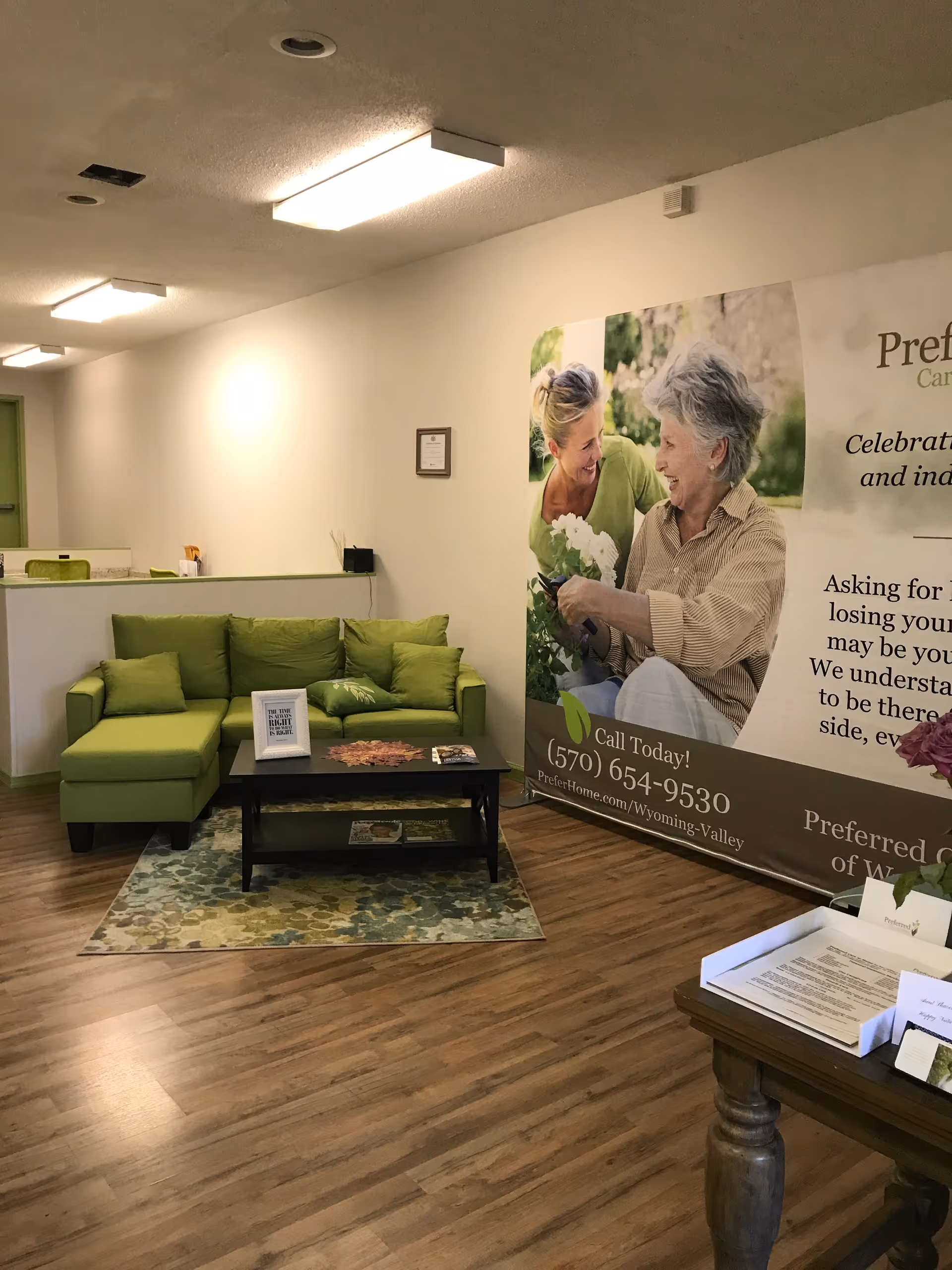 Lobby with green sofa, coffee table, and large promotional banner for Preferred Care