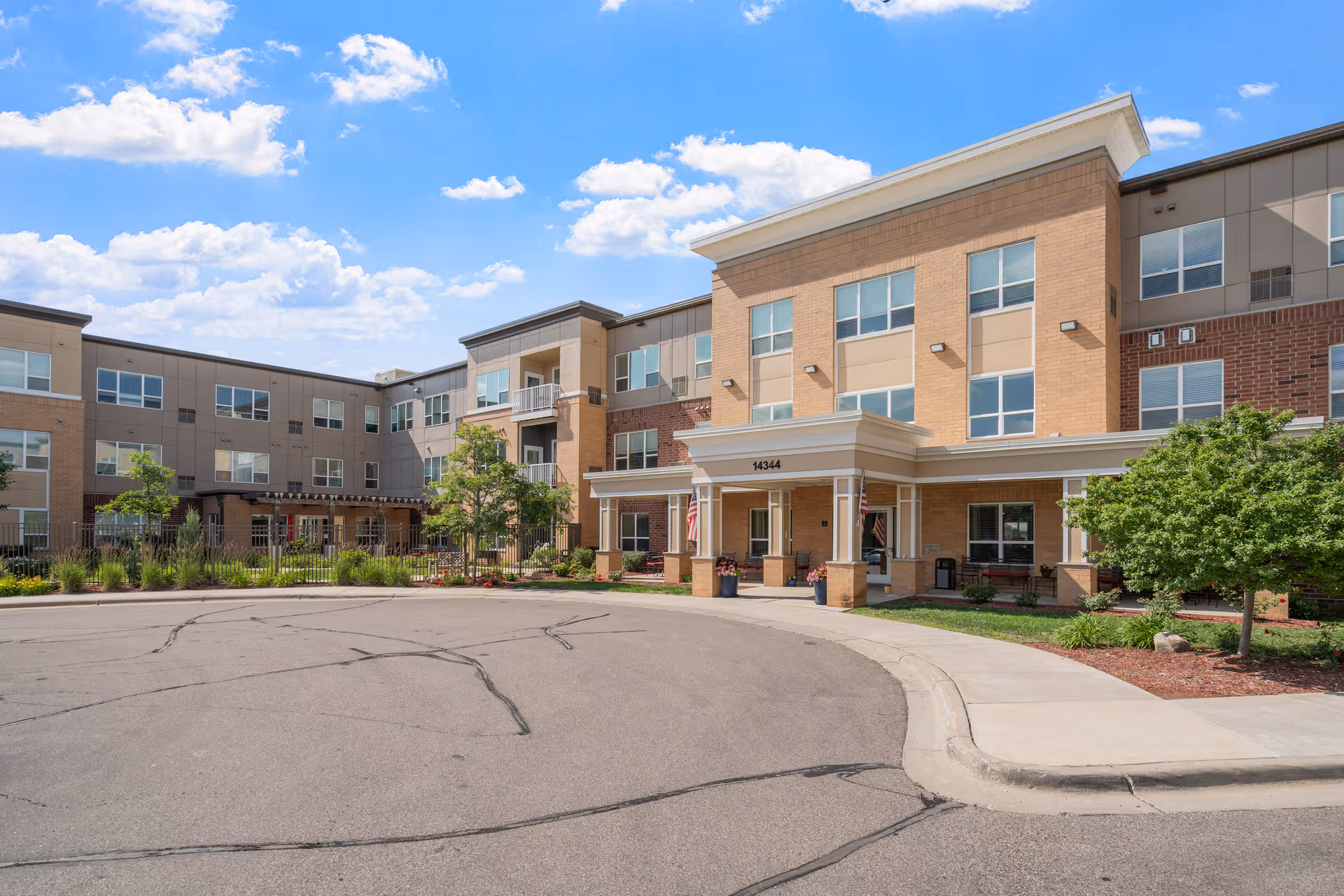 Front view of a modern multi-story senior living building with landscaped entrance.