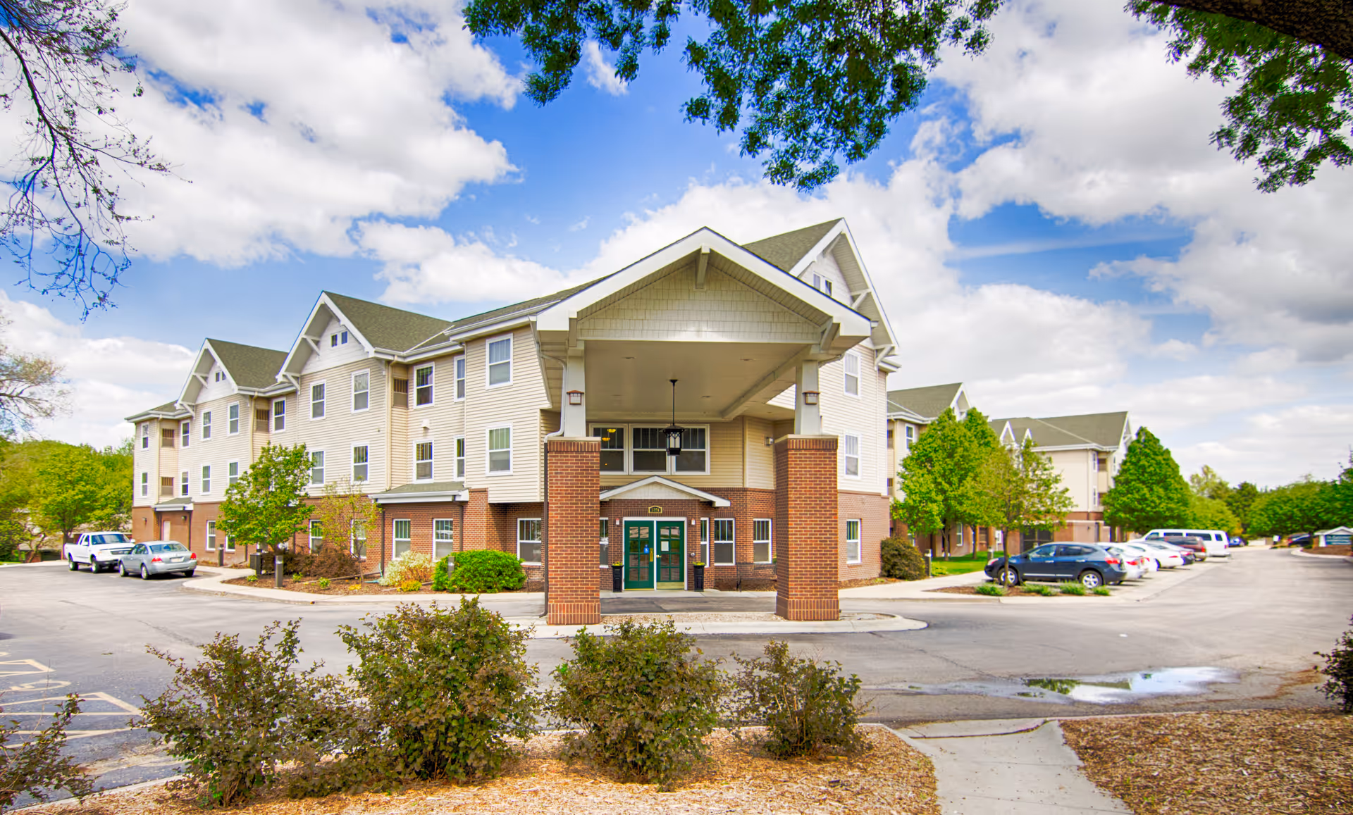 Exterior view of The Lexington Assisted Living building with parking and trees.