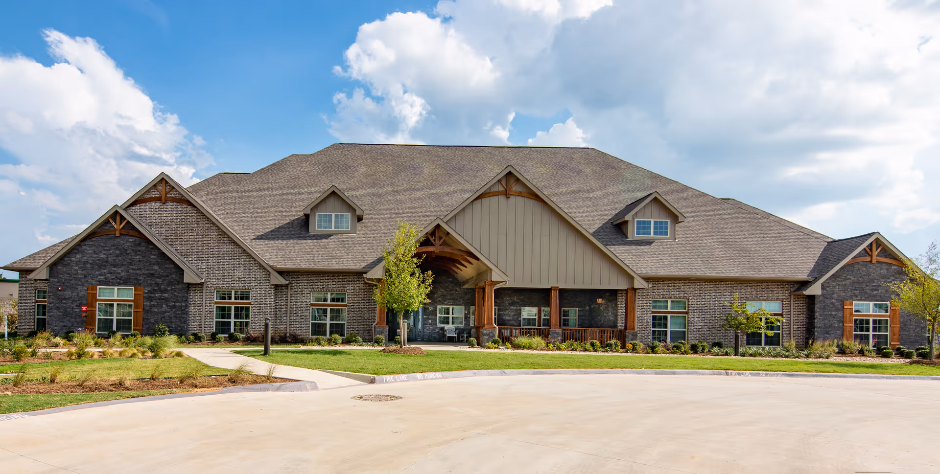 Front view of a brick assisted living facility with a covered entrance and landscaping.