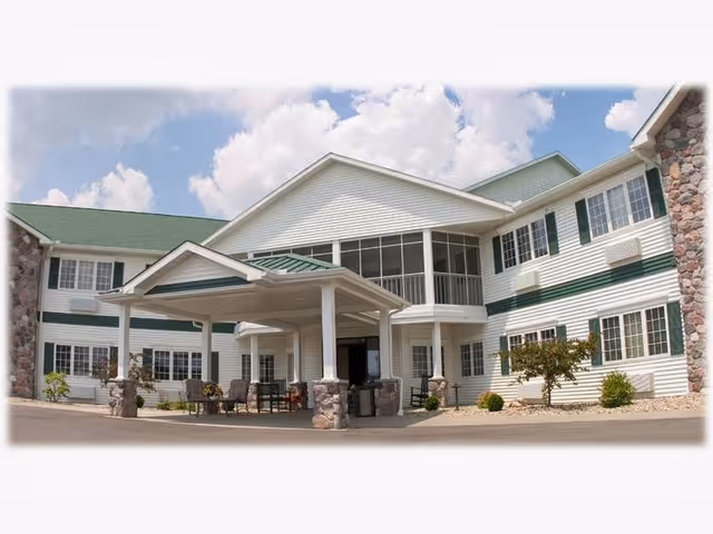 Heritage House Senior Living exterior features a covered entrance with seating and stone columns.