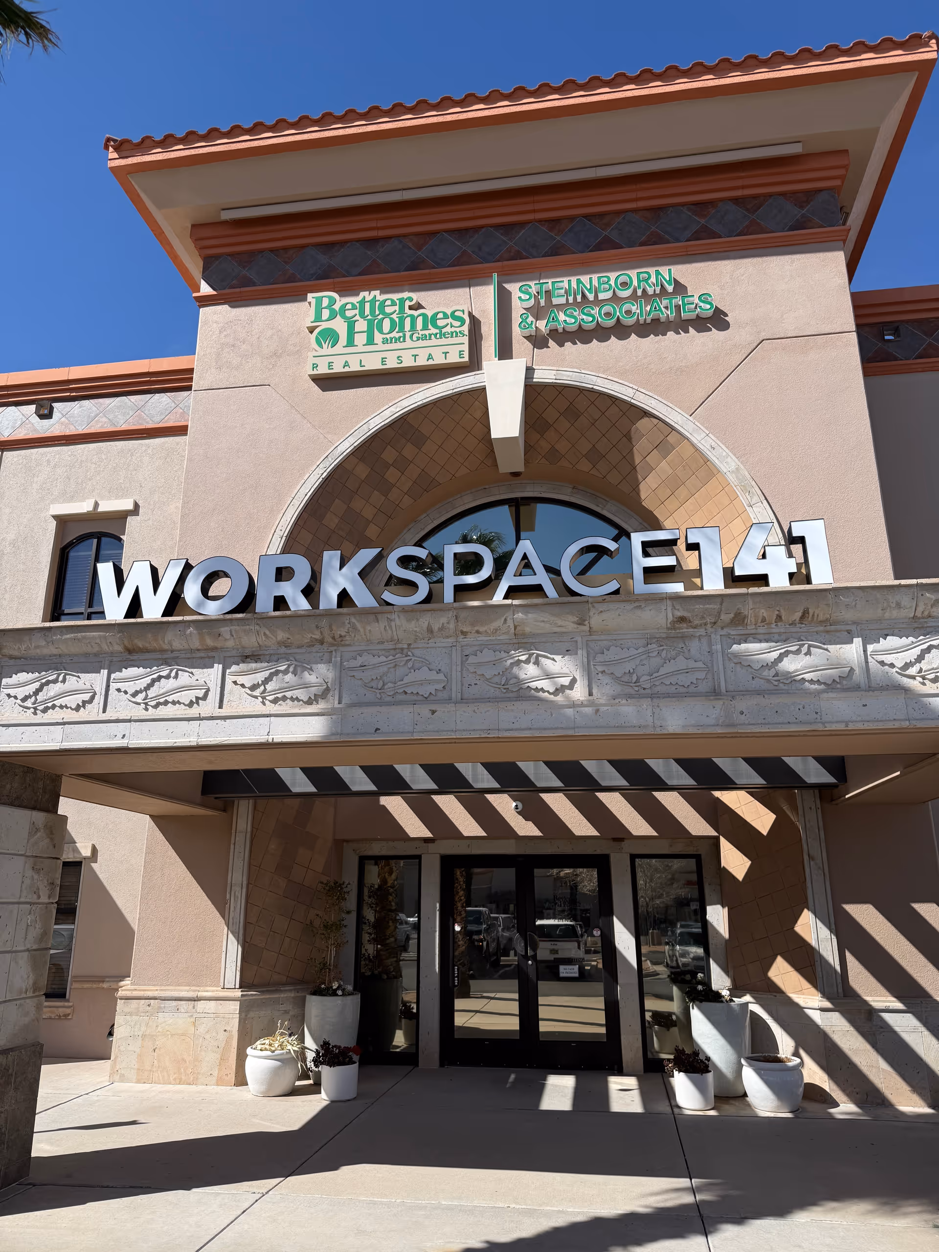 Facade of a commercial building with a large WORKSPACE41 sign and entrance plants.