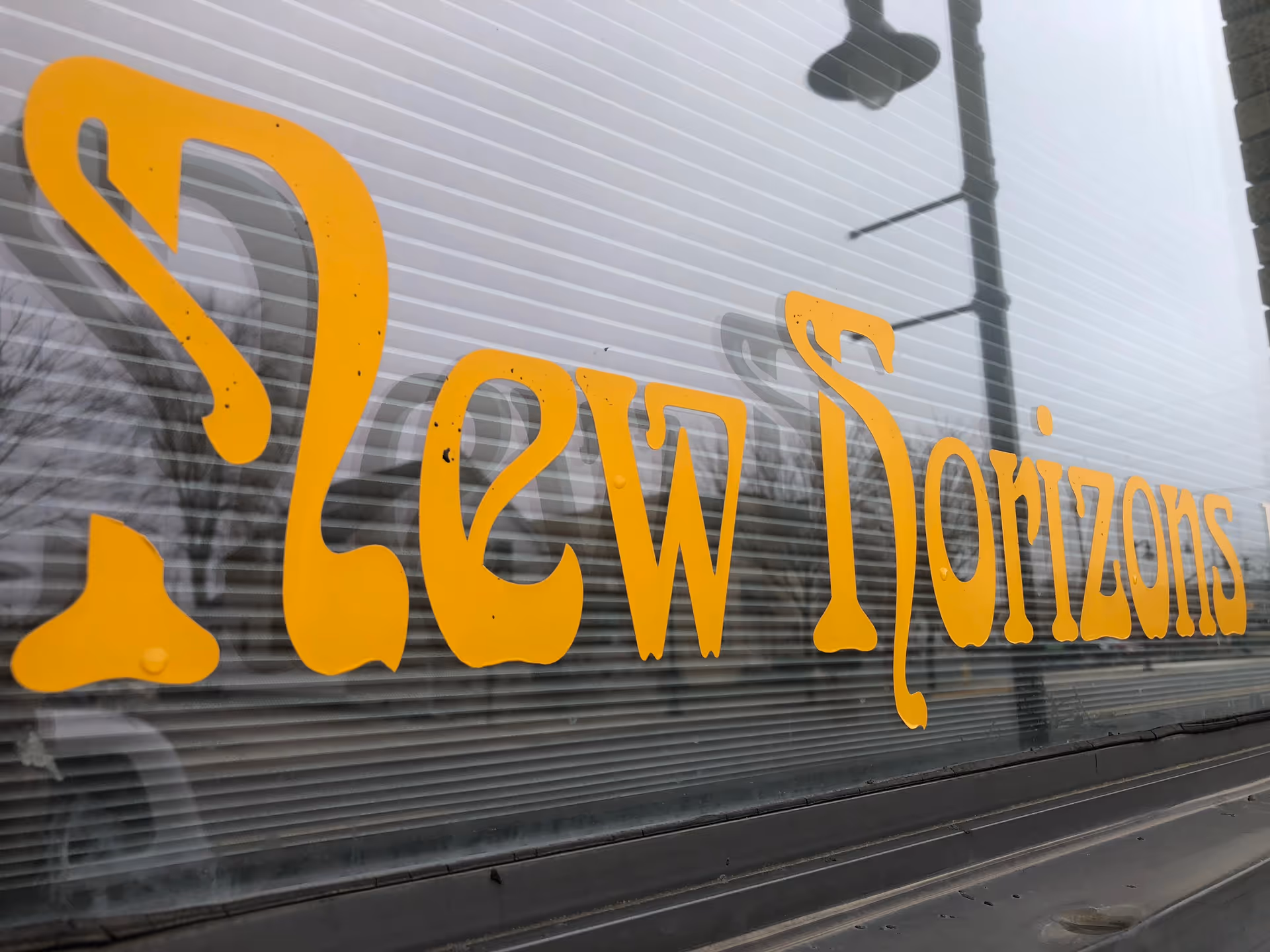 Close-up of yellow 'New Horizons' sign on a glass building exterior.