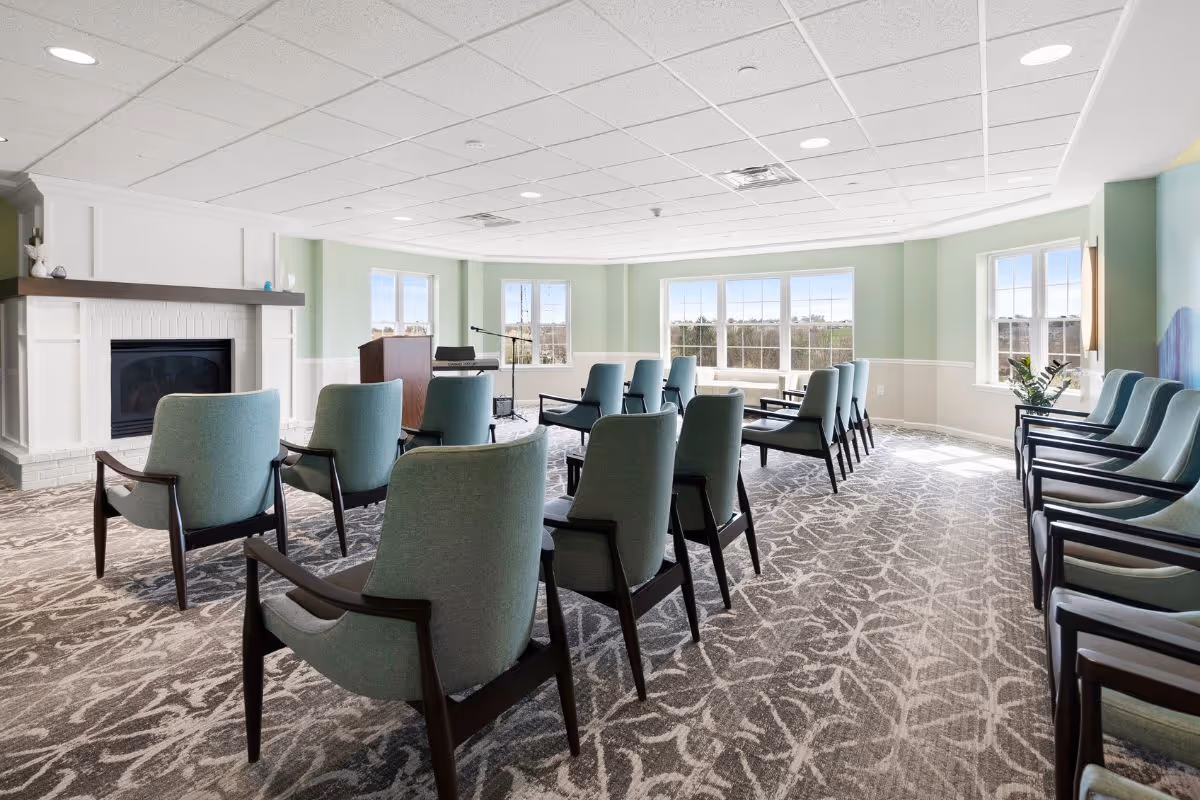 Senior living common room with rows of blue-green chairs, a fireplace, and a podium.