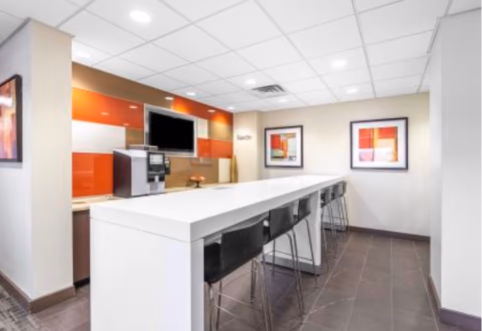 Bright modern kitchen and dining counter with stools, orange tile backsplash, wall art.