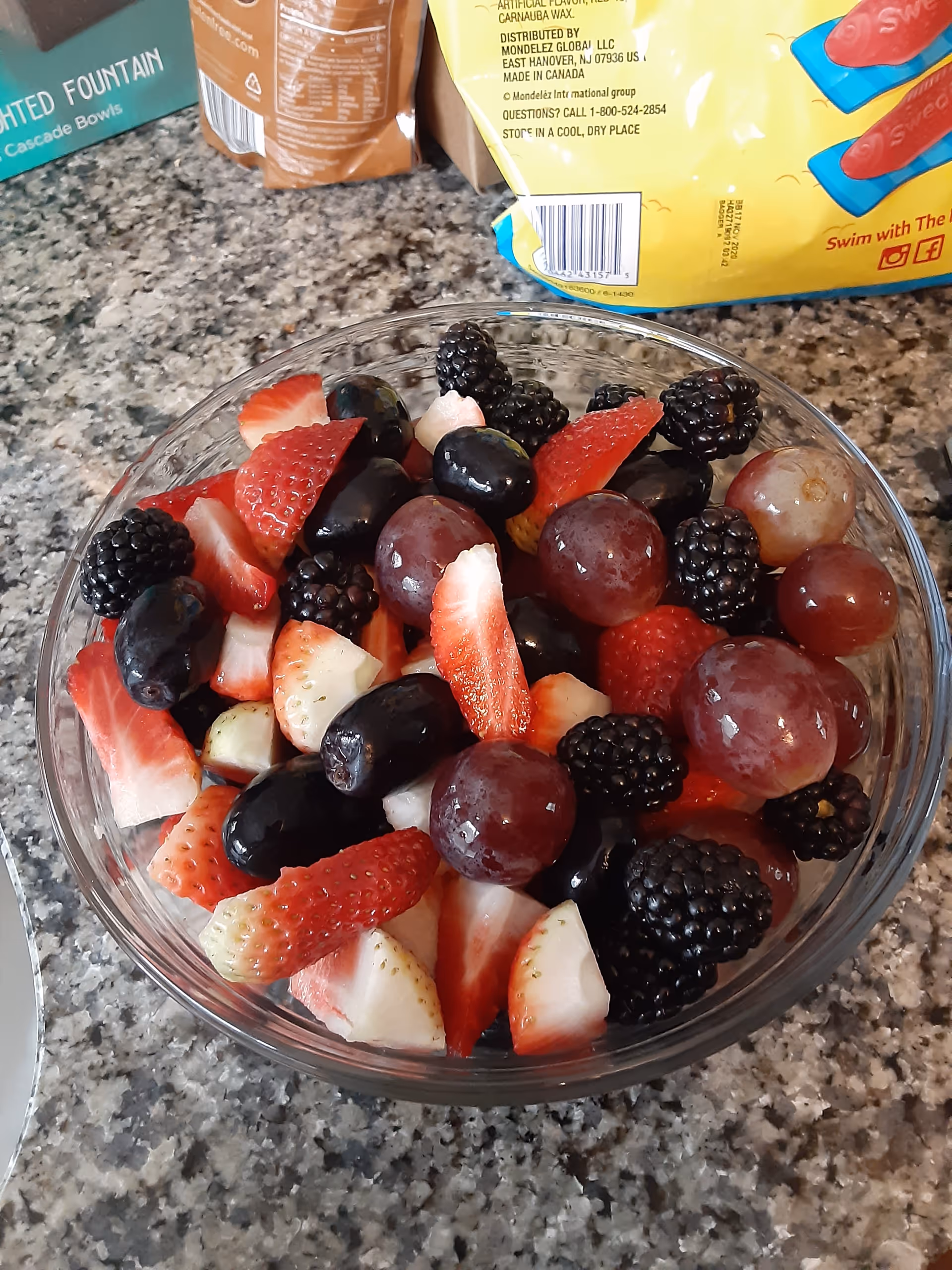 Bowl of mixed berries and fruit on a kitchen counter.