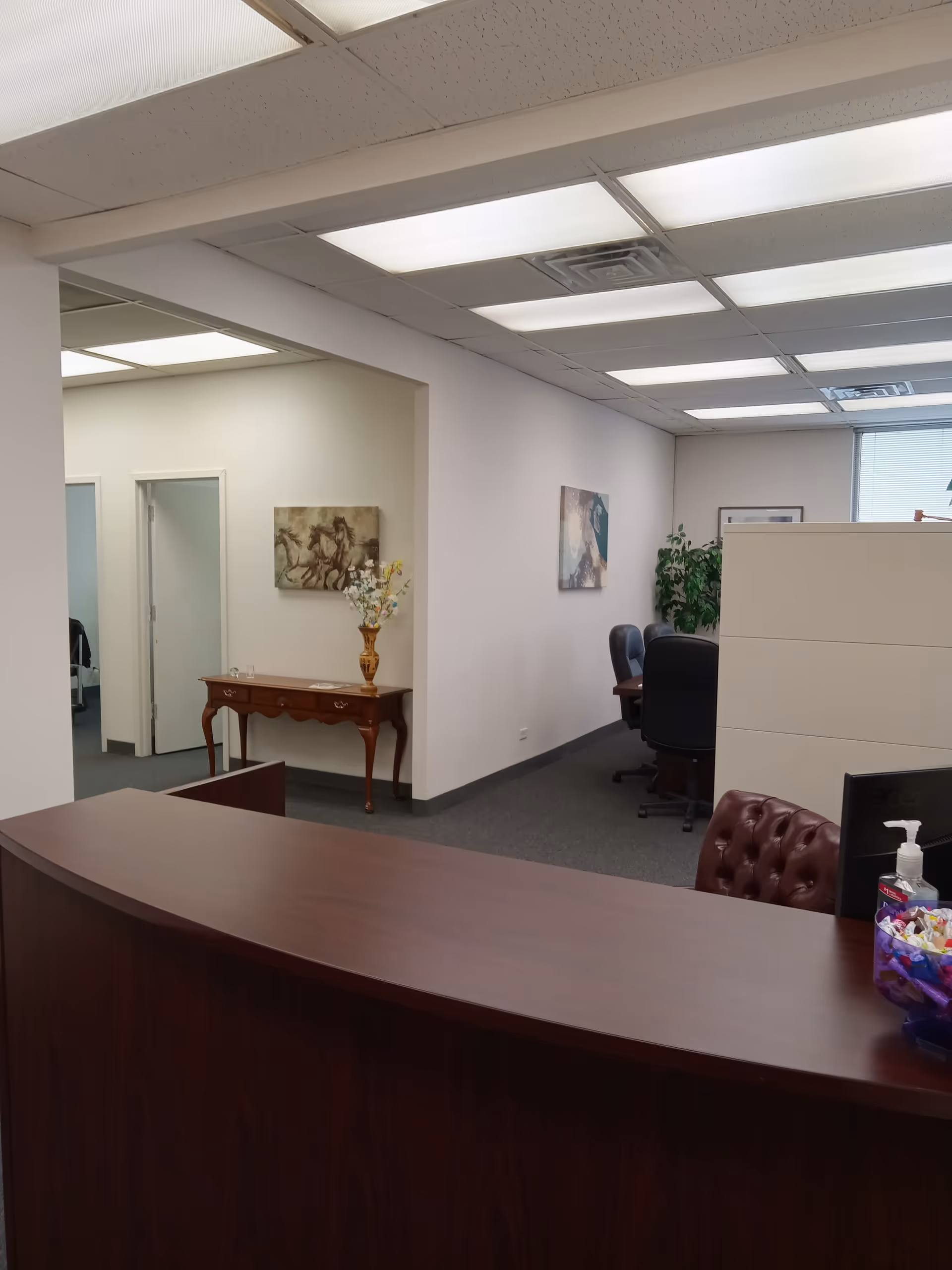 Reception desk in a senior living facility lobby with chairs and artwork.