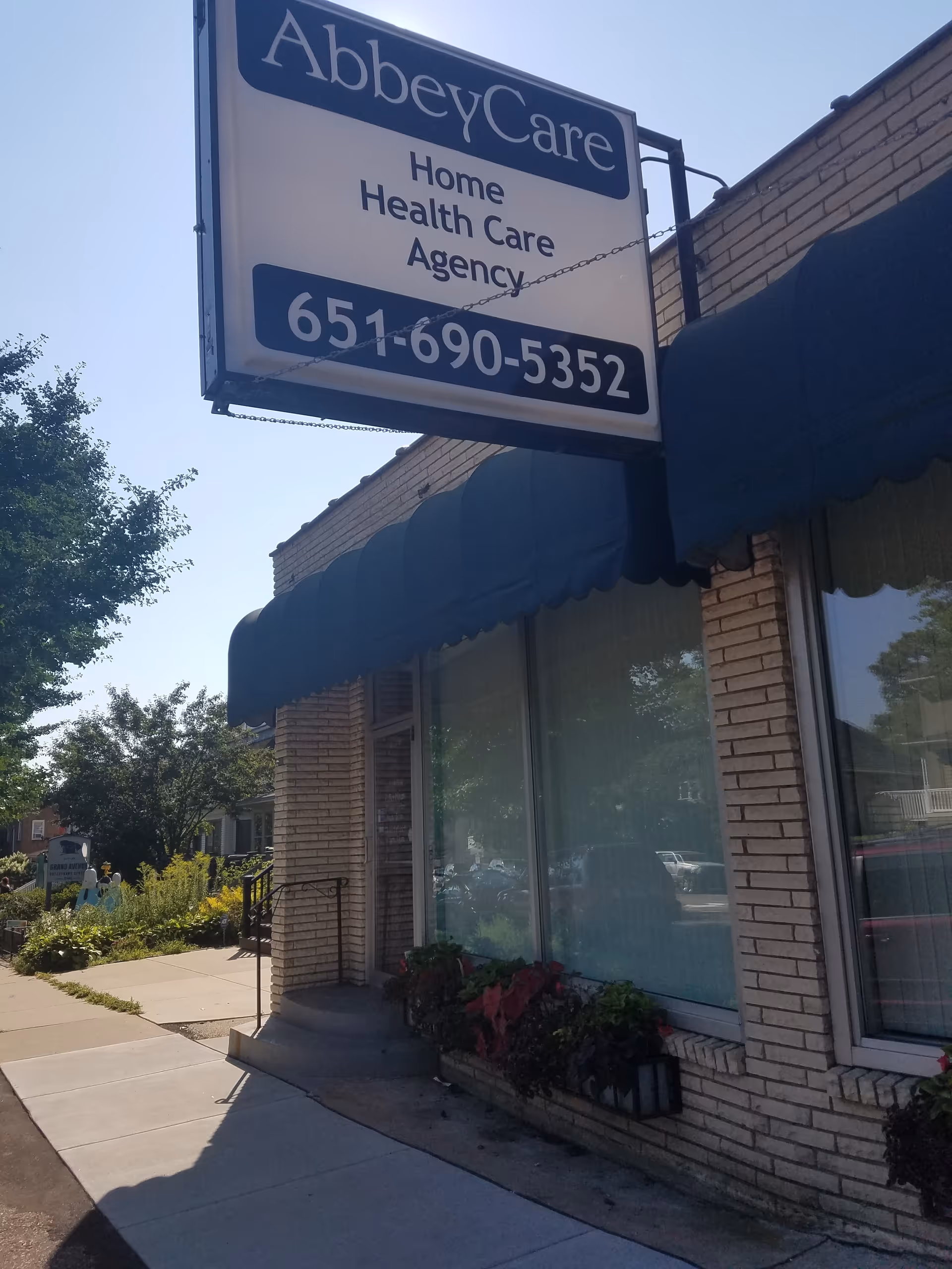 Exterior view of AbbeyCare Home Health Care Agency sign on a brick building with blue awnings.