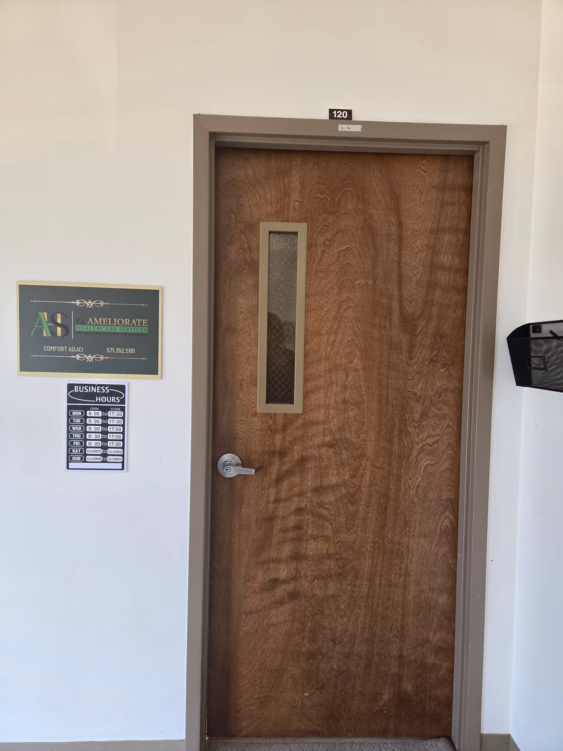Wooden interior door labeled 120 in a hallway with business hours sign beside it.