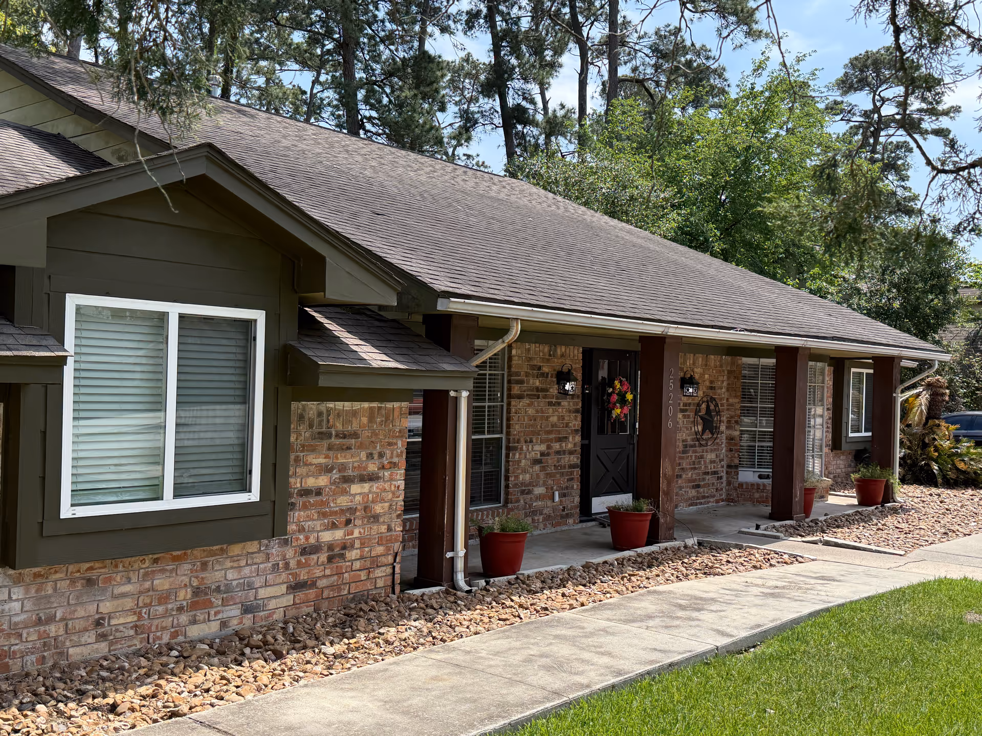 Single-story brick facility front with porch, pillars, wreath-decorated door, and gravel landscaping.