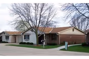 Spurgeon Manor exterior: a single-story brick senior living facility with a manicured lawn.