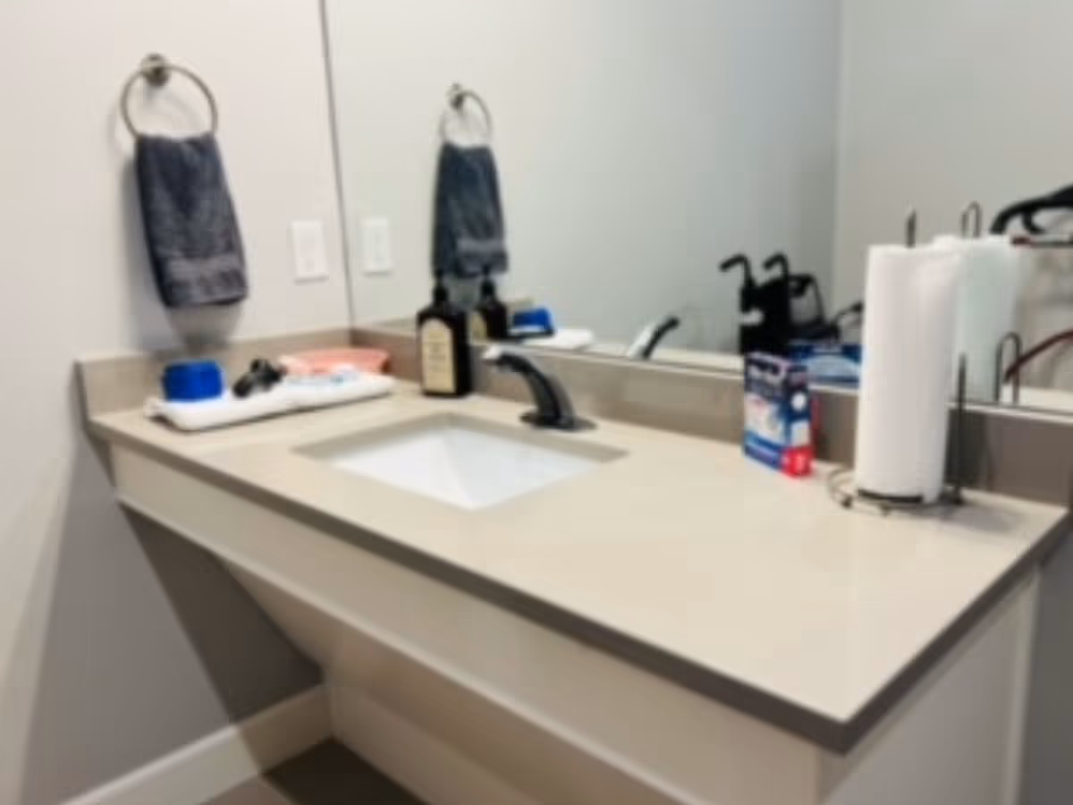 Bathroom vanity with sink, faucet, towels, and toiletries on the counter.