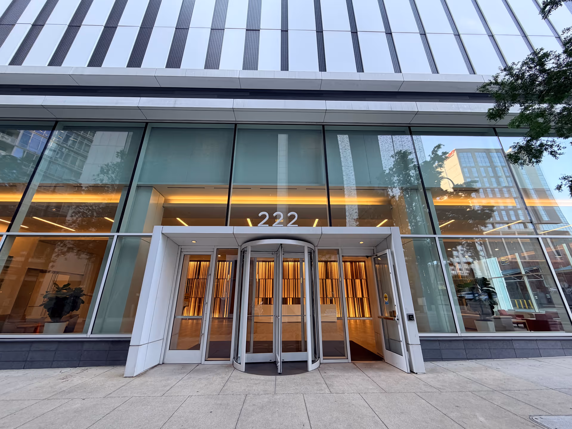 Glass-front building entrance with revolving doors and the number 222 above.