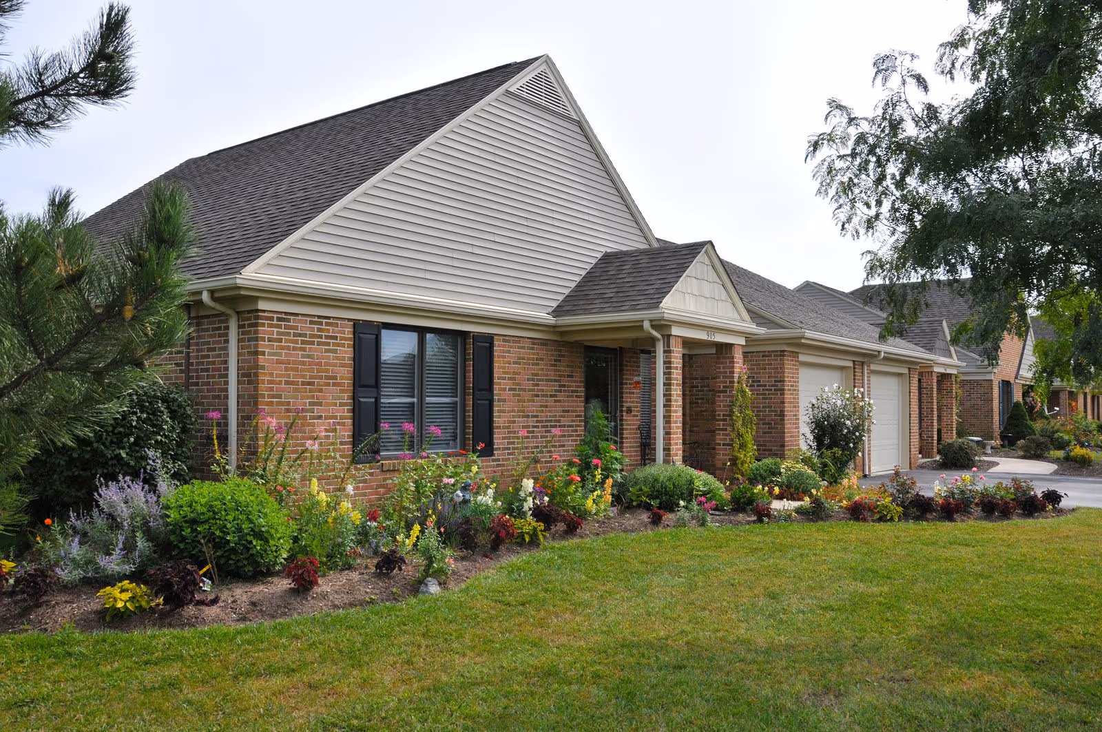 Row of brick senior living cottages with neatly landscaped front yards.