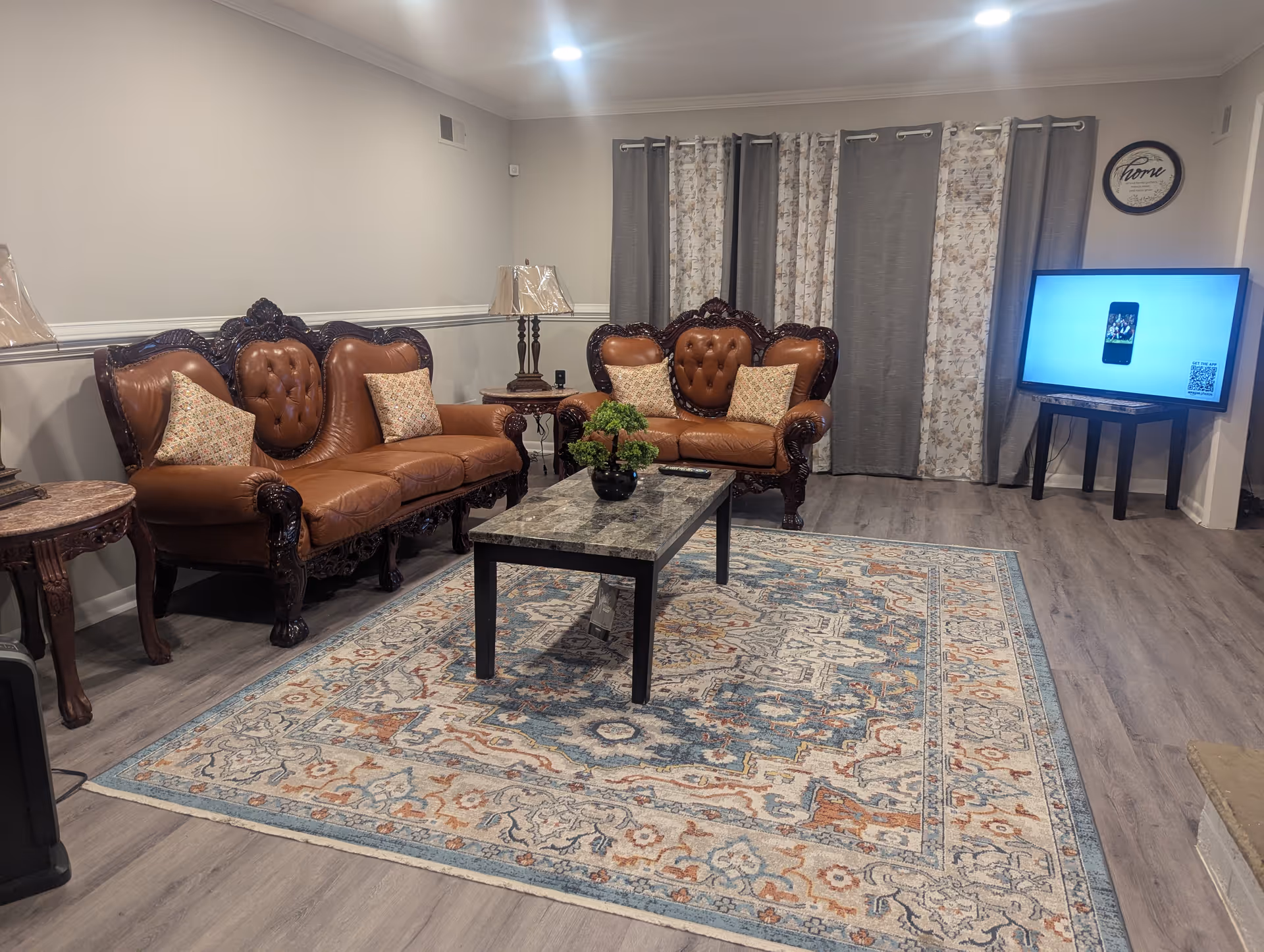 Senior living lounge with brown leather seating, coffee table, rug, and TV.