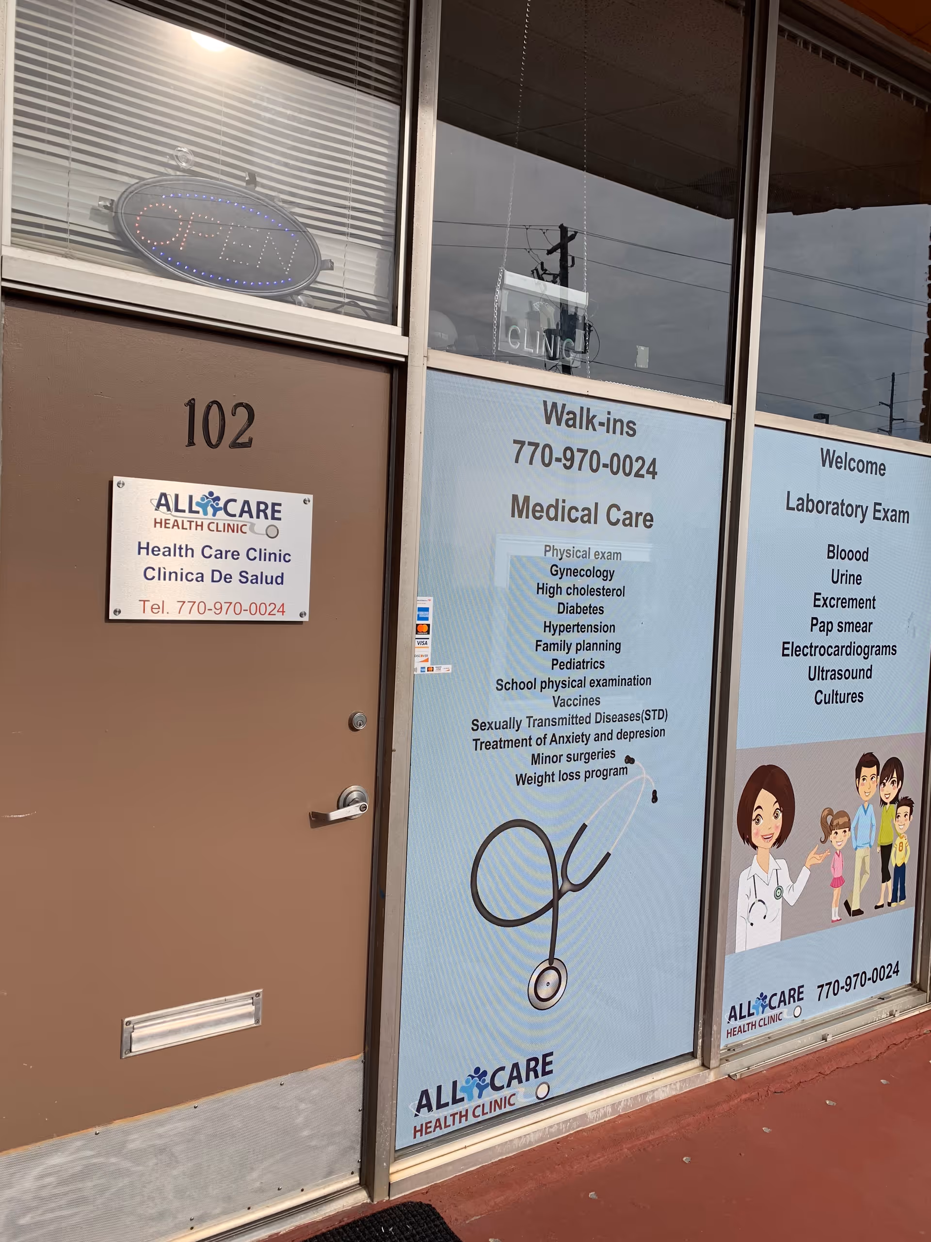 Exterior clinic storefront with All Care Health Clinic signage and medical posters.