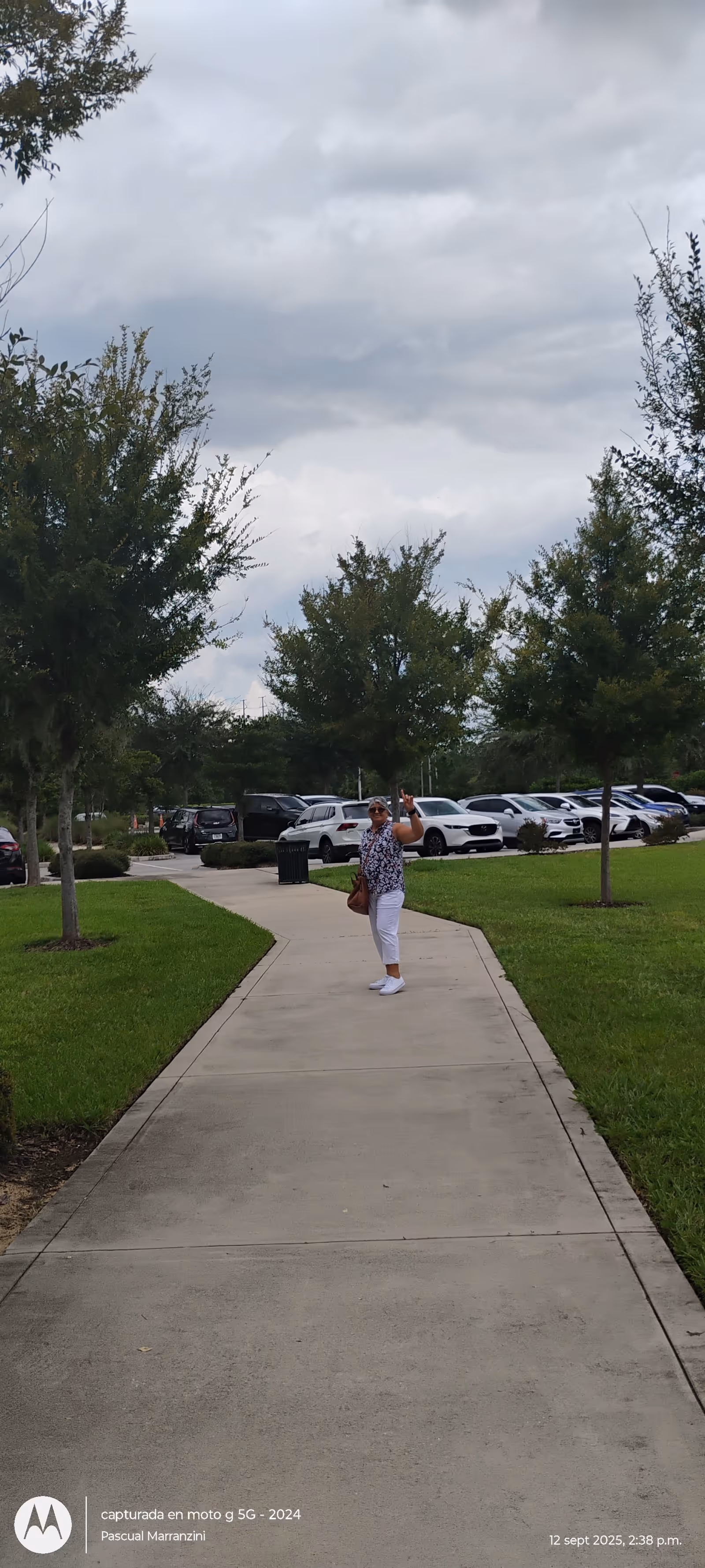 A person walks on a curved sidewalk outside a senior living facility amid trees.