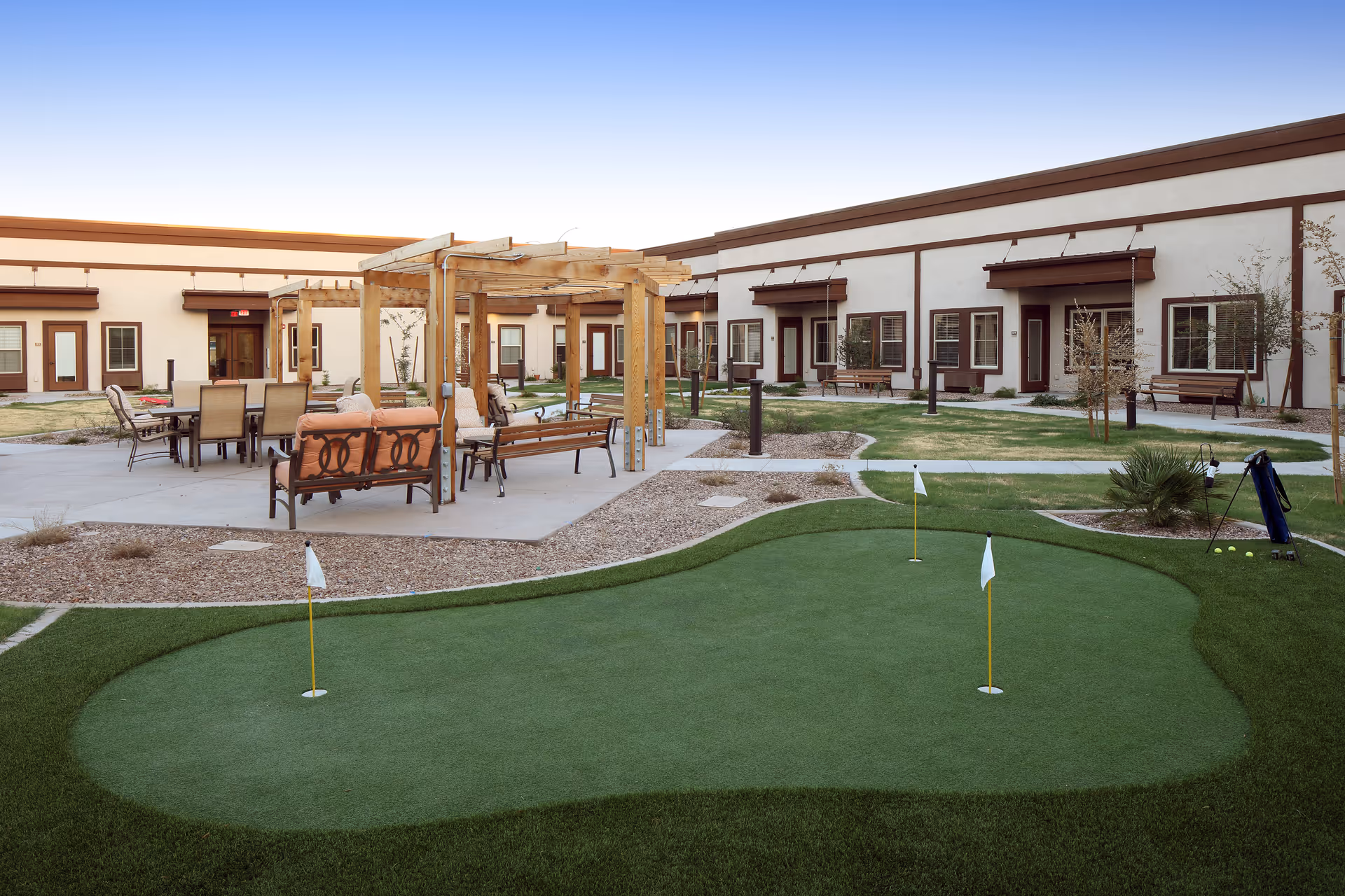 Outdoor courtyard of Sky Vista with benches, pergola, and a putting green.