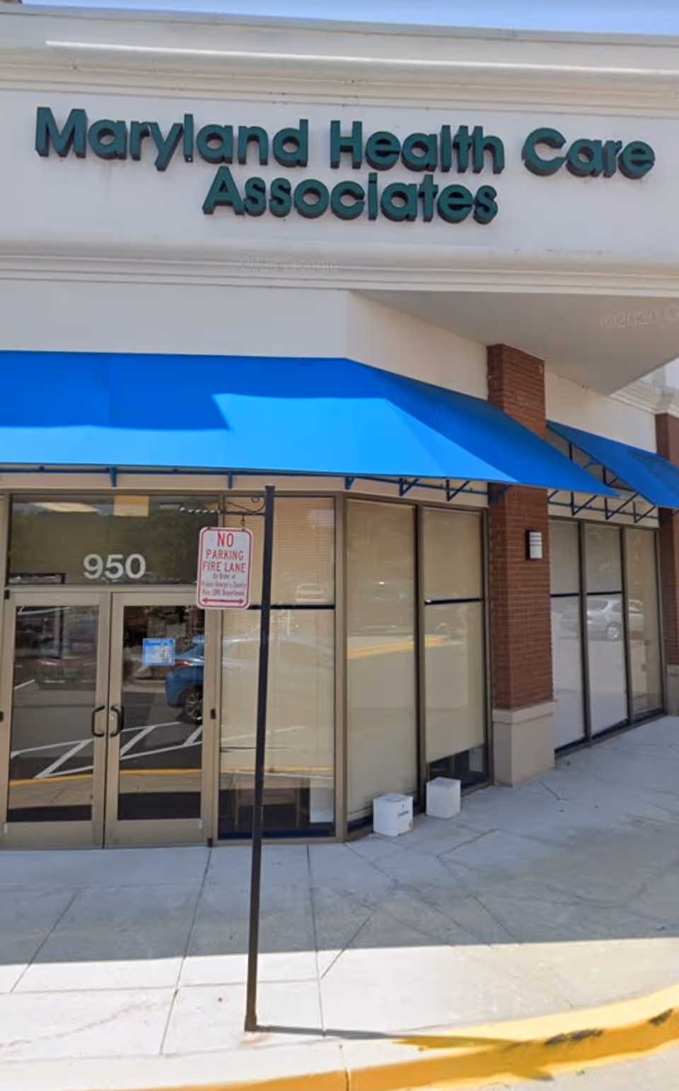 Exterior view of Maryland Health Care Associates storefront with blue awning and glass doors.