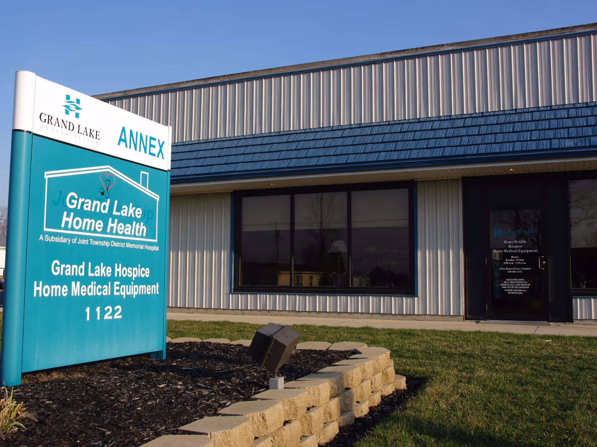 Exterior view of Grand Lake Home Health facility with teal sign and entrance door.