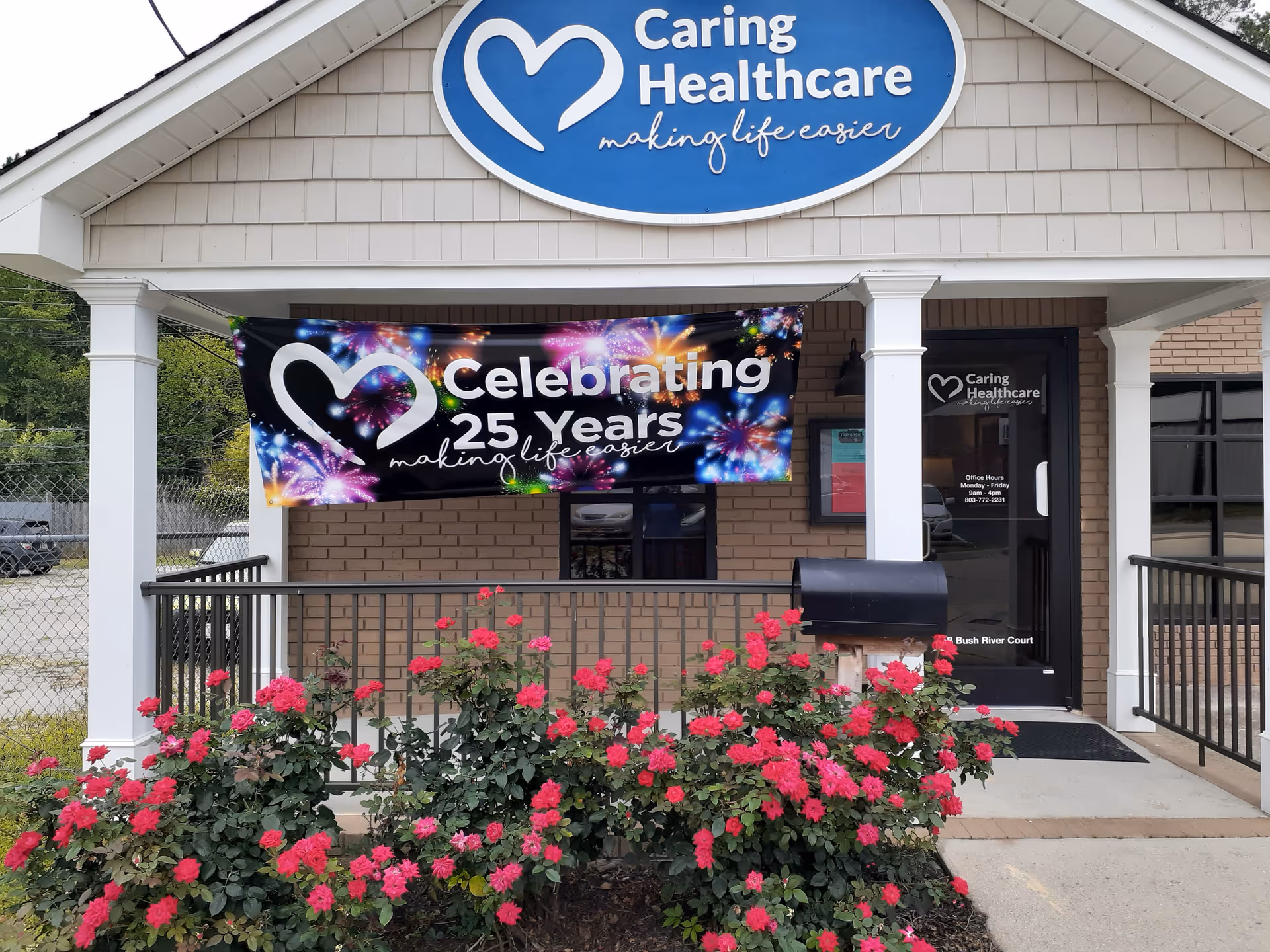 Exterior view of Caring Healthcare facility entrance with a celebratory banner and pink roses.