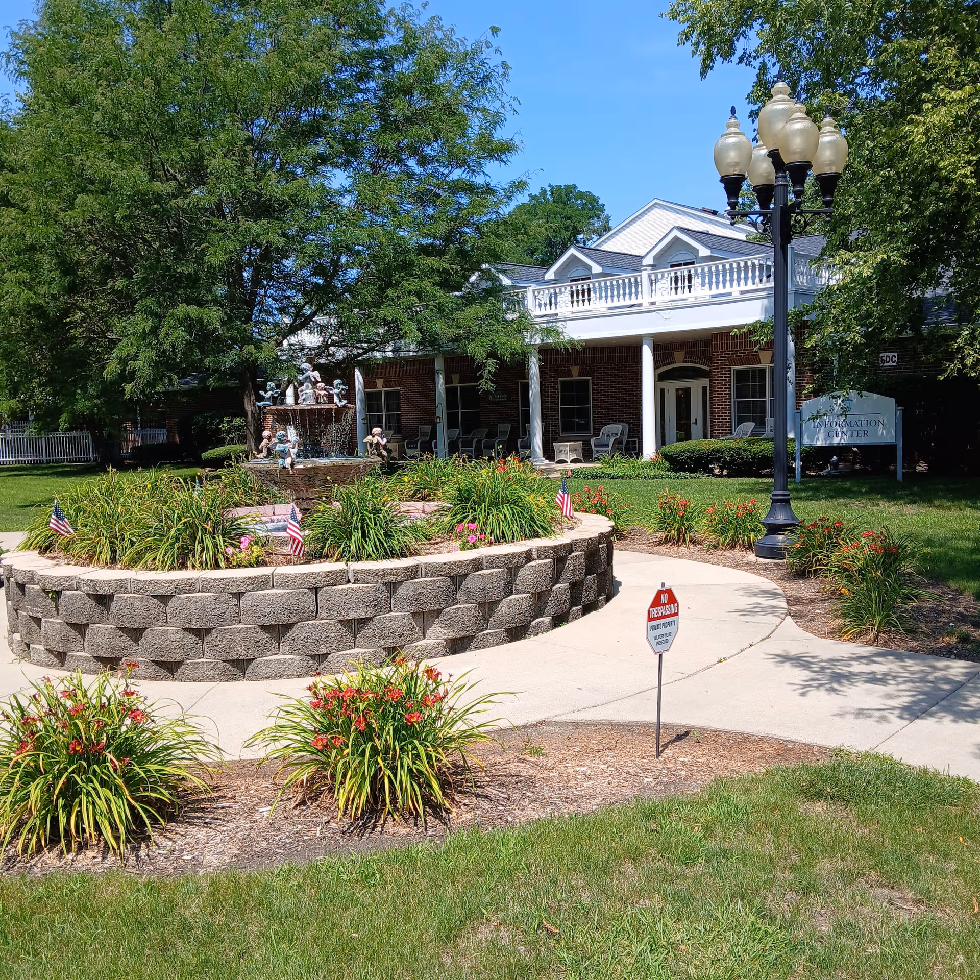 Exterior view of Cottages of Fox Lake showing a circular stone fountain, walkway, and landscaped lawn
