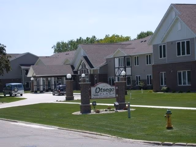 Exterior view of a senior living facility with a manicured lawn and entrance sign.