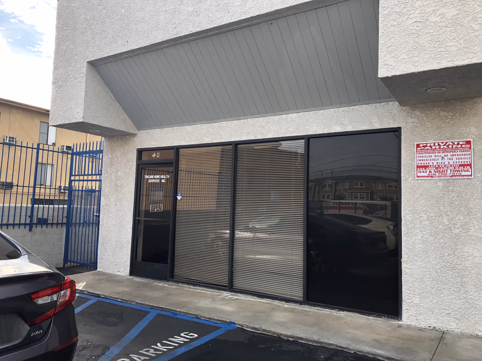 Exterior of Tri Care Home Health Services entrance with glass doors and a parking sign.