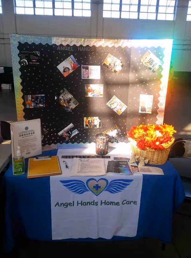 Indoor information booth with a table, banner, and display board for Angel Hands Home Care.