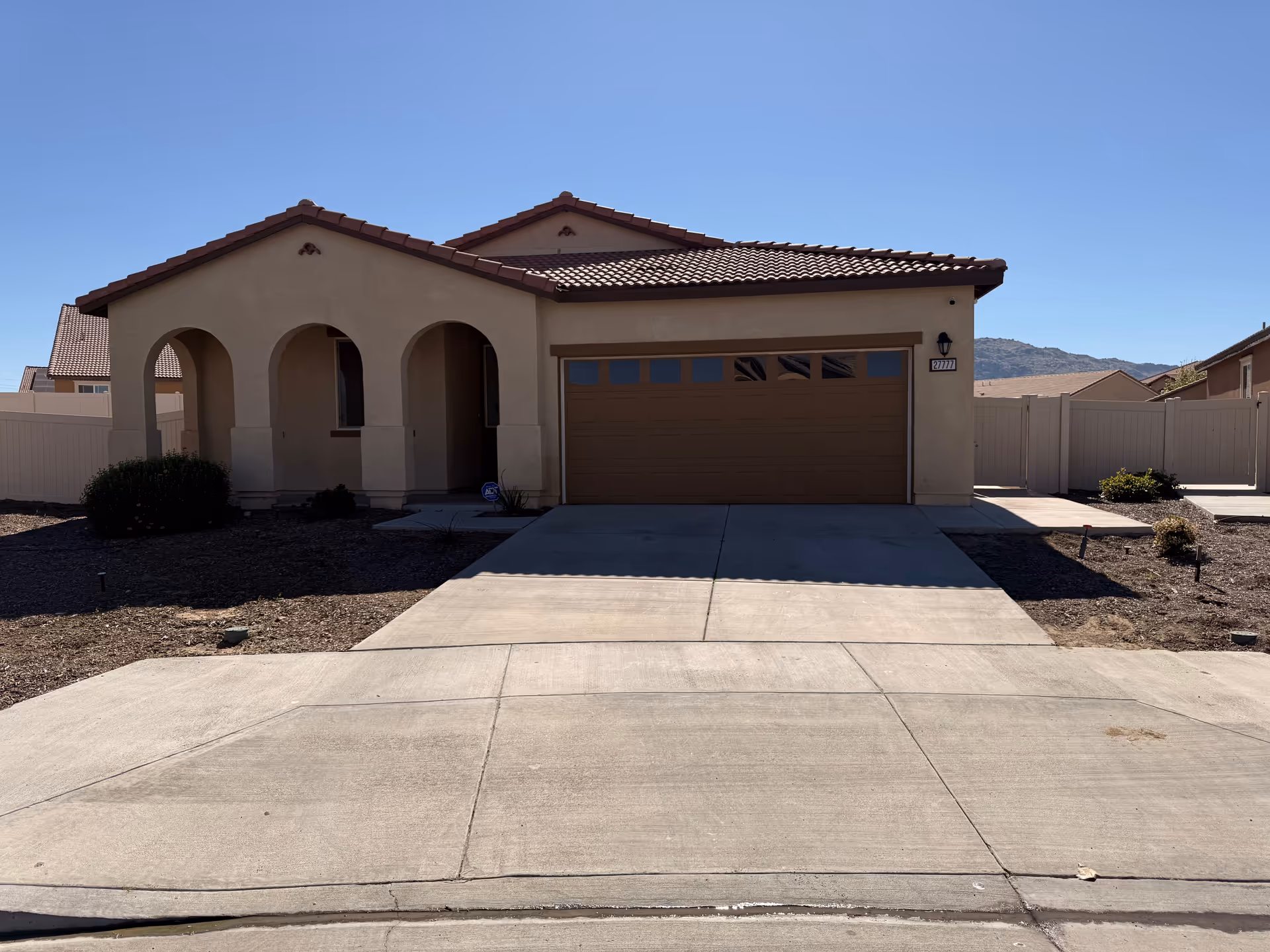 A modern single-story beige house with arched porch and a two-car garage.