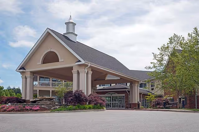 Front entrance of a large retirement village building with a covered drop-off area.