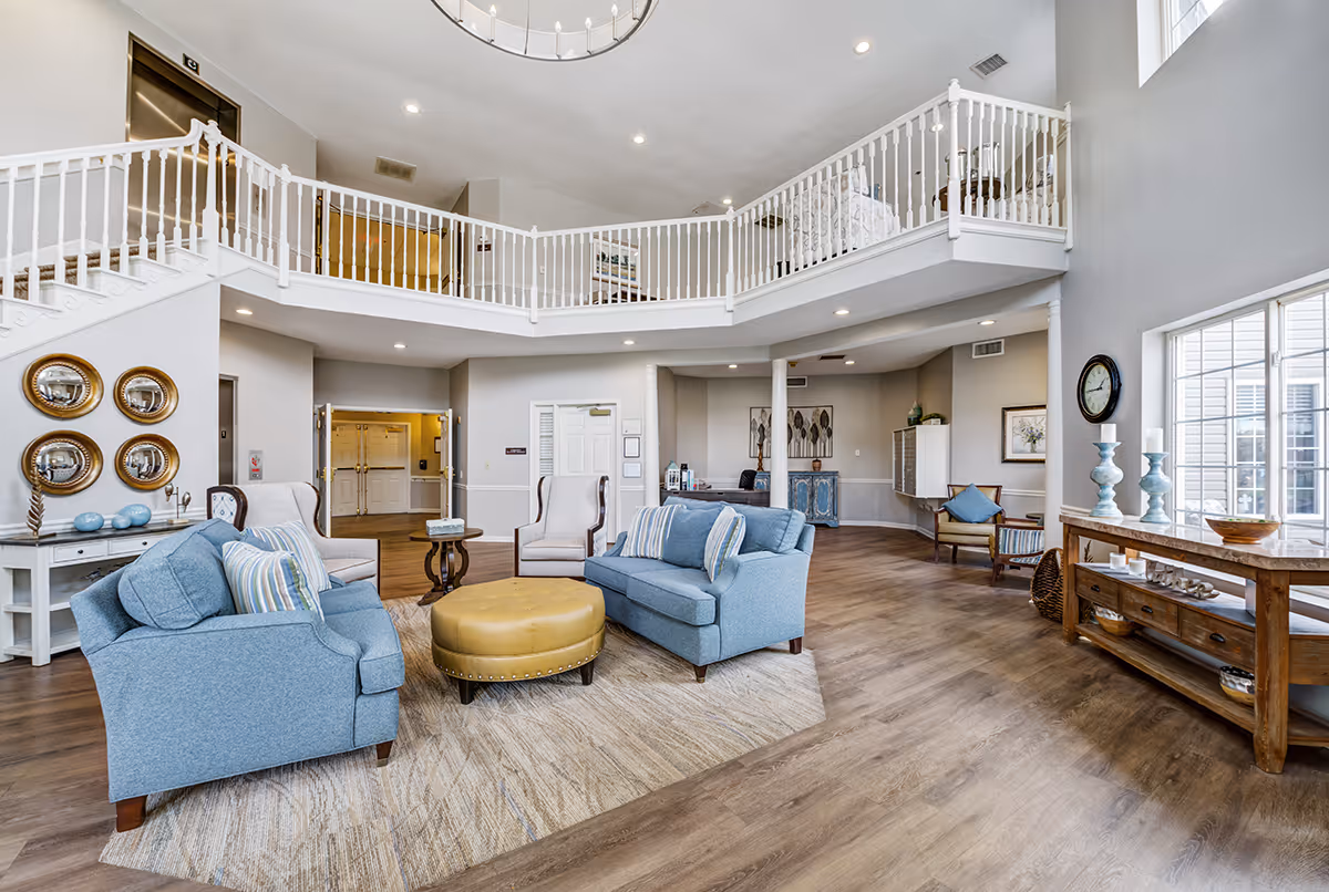 Two blue upholstered sofas and chairs form a lounge area in a bright senior living lobby.