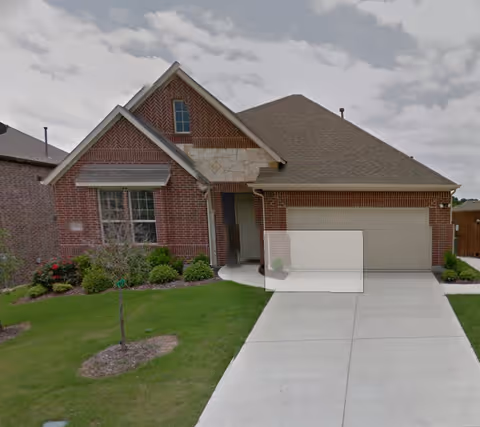 Brick residential front view of a care home with a two-car garage and landscaped lawn