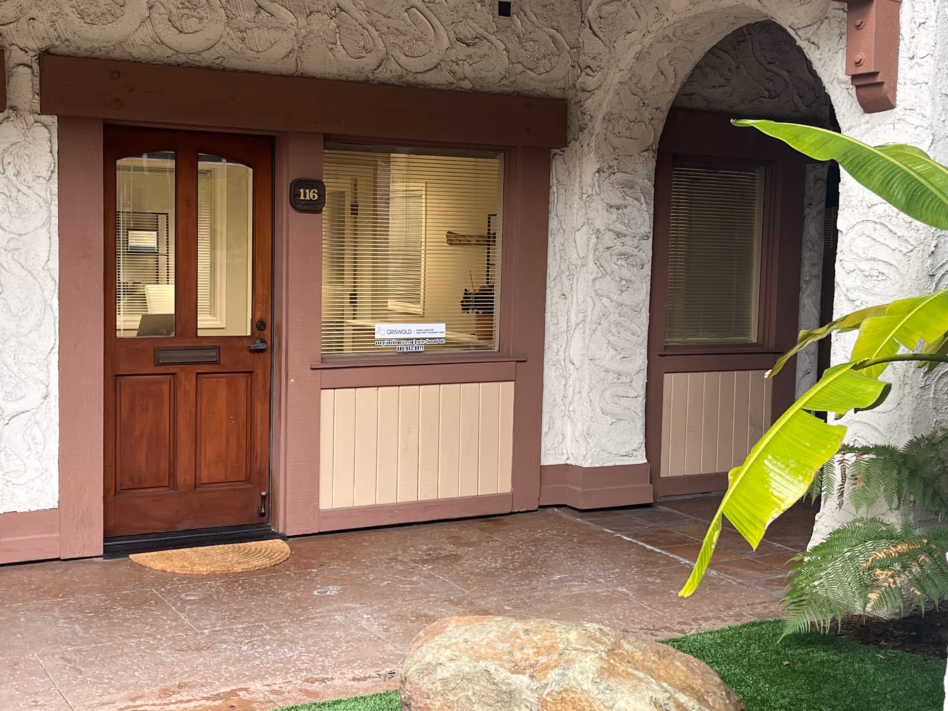 Exterior entrance of a senior care facility with wooden doors and arches.