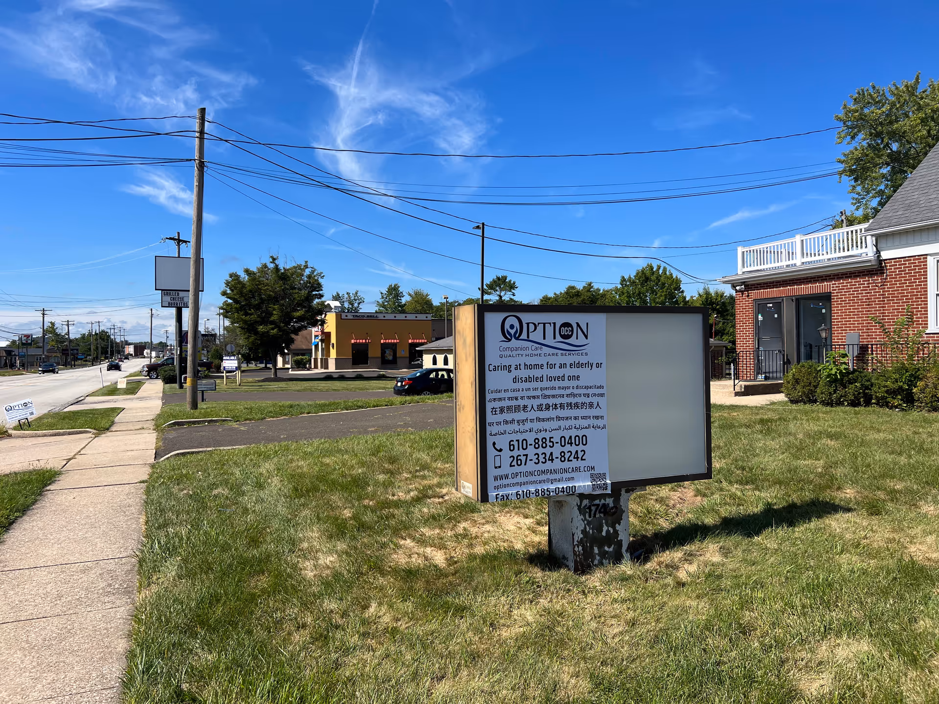 Outdoor street scene with a grassy lot sign advertising Option Companion Care.