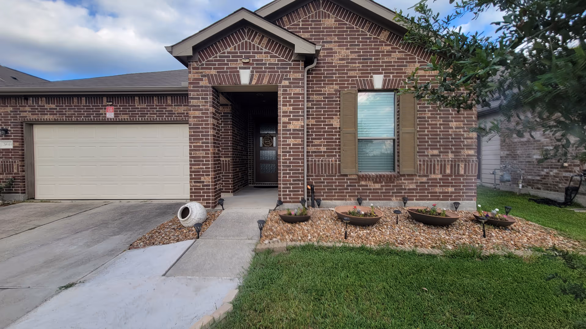 Front view of a brick residential building with a two-car garage and manicured yard.