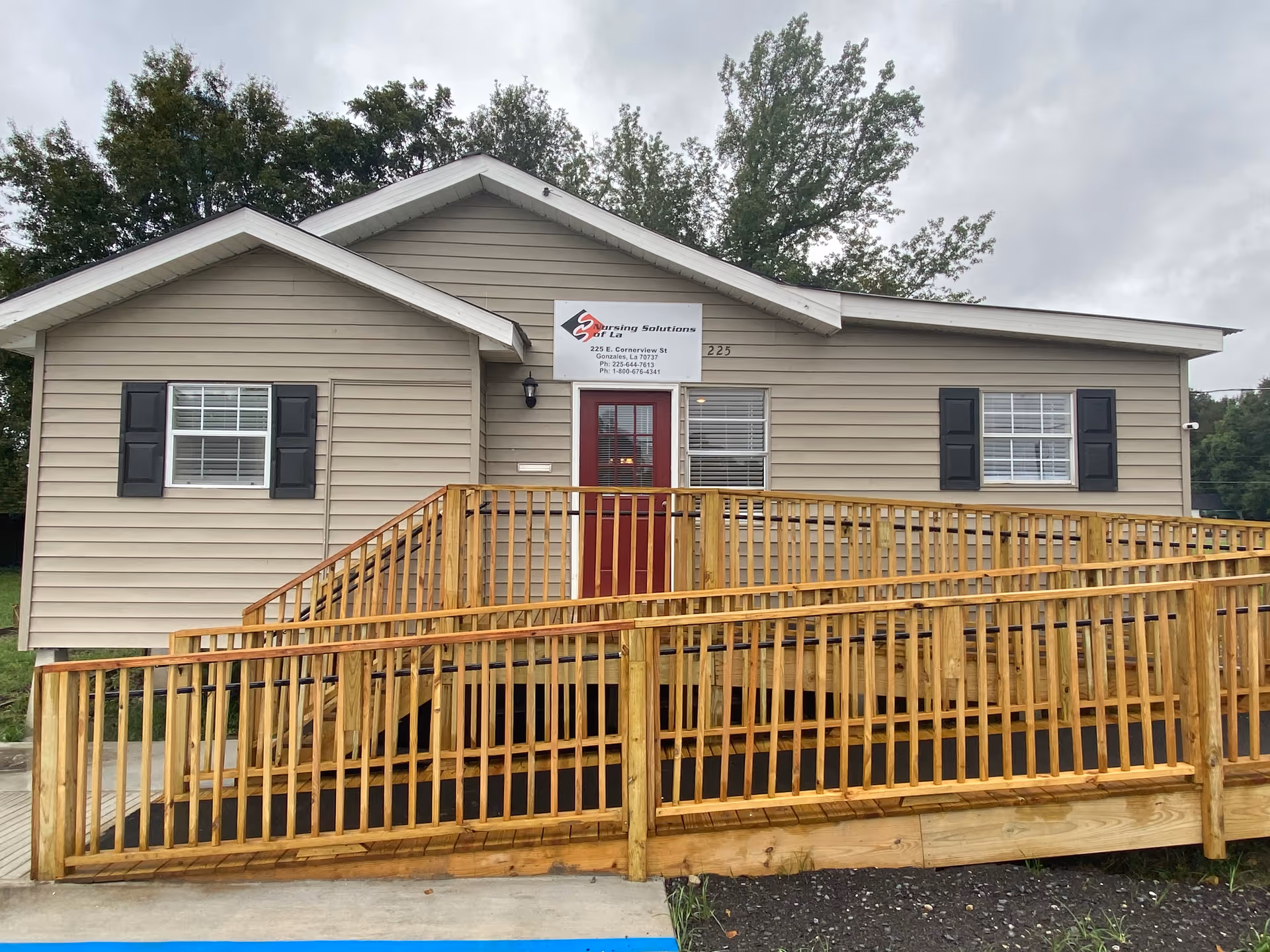 Front view of a single-story beige elder care facility with a wooden ramp.
