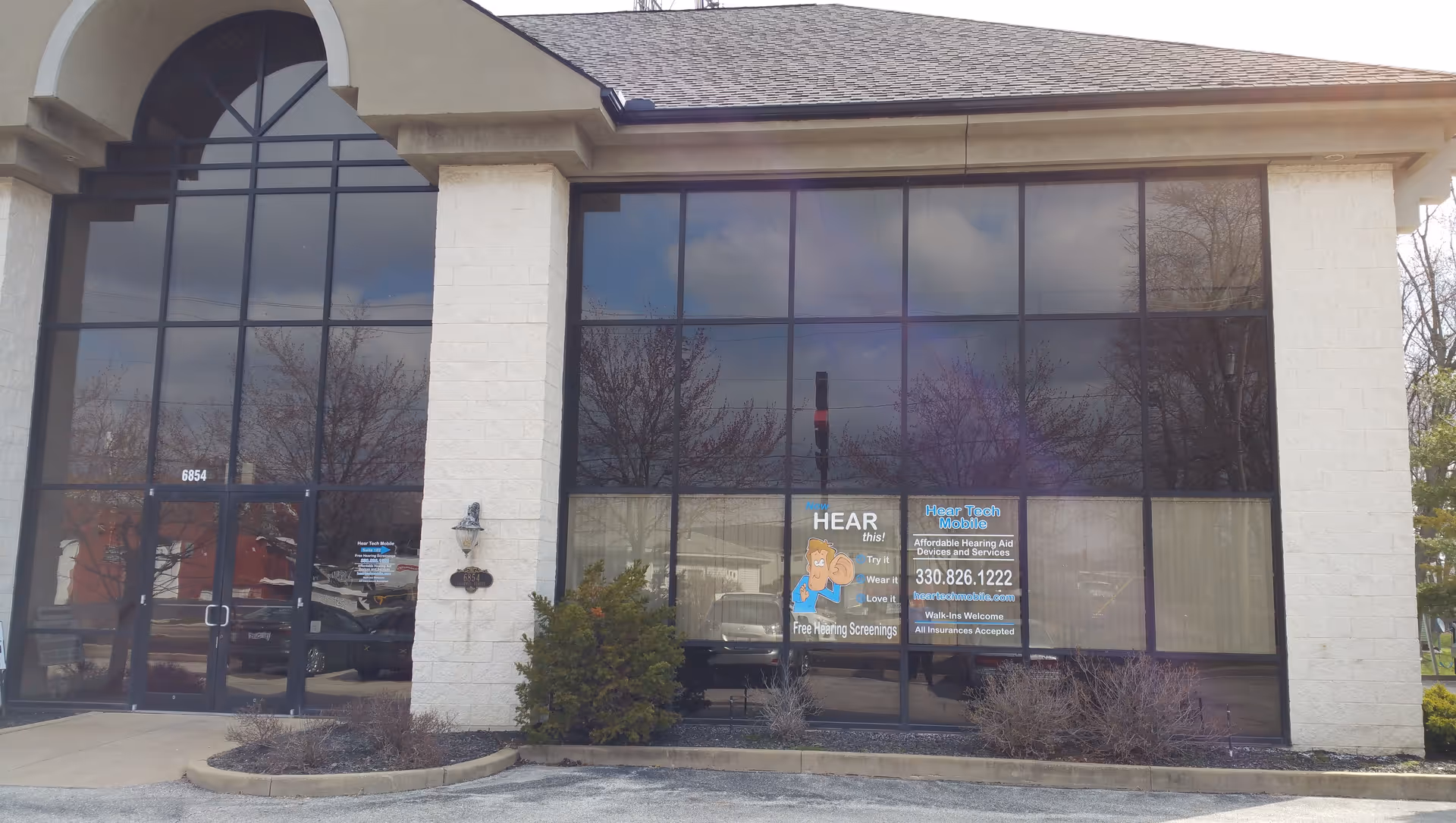 Exterior view of Hear Tech Mobile & Hearing Care Center storefront with large glass windows.
